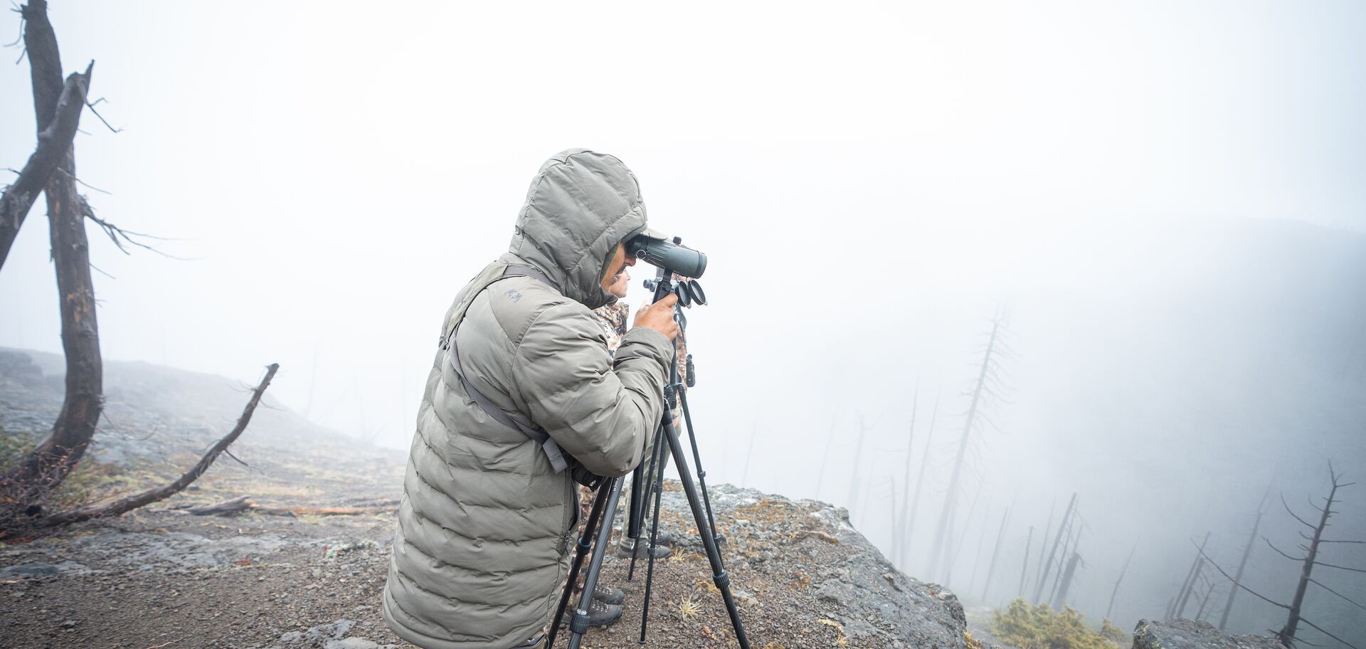 Hunter uses scope on ridge for Western hunt.