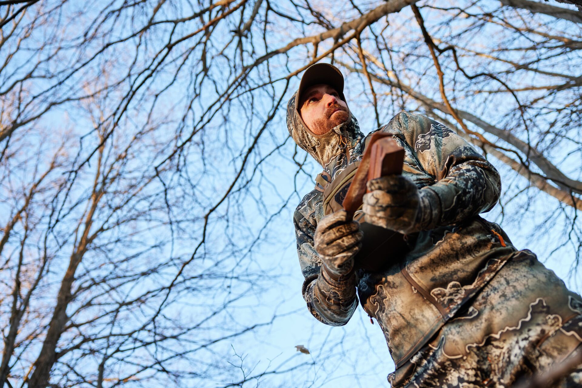 A hunter in camo uses a turkey call, hunt Osceola turkey concept.