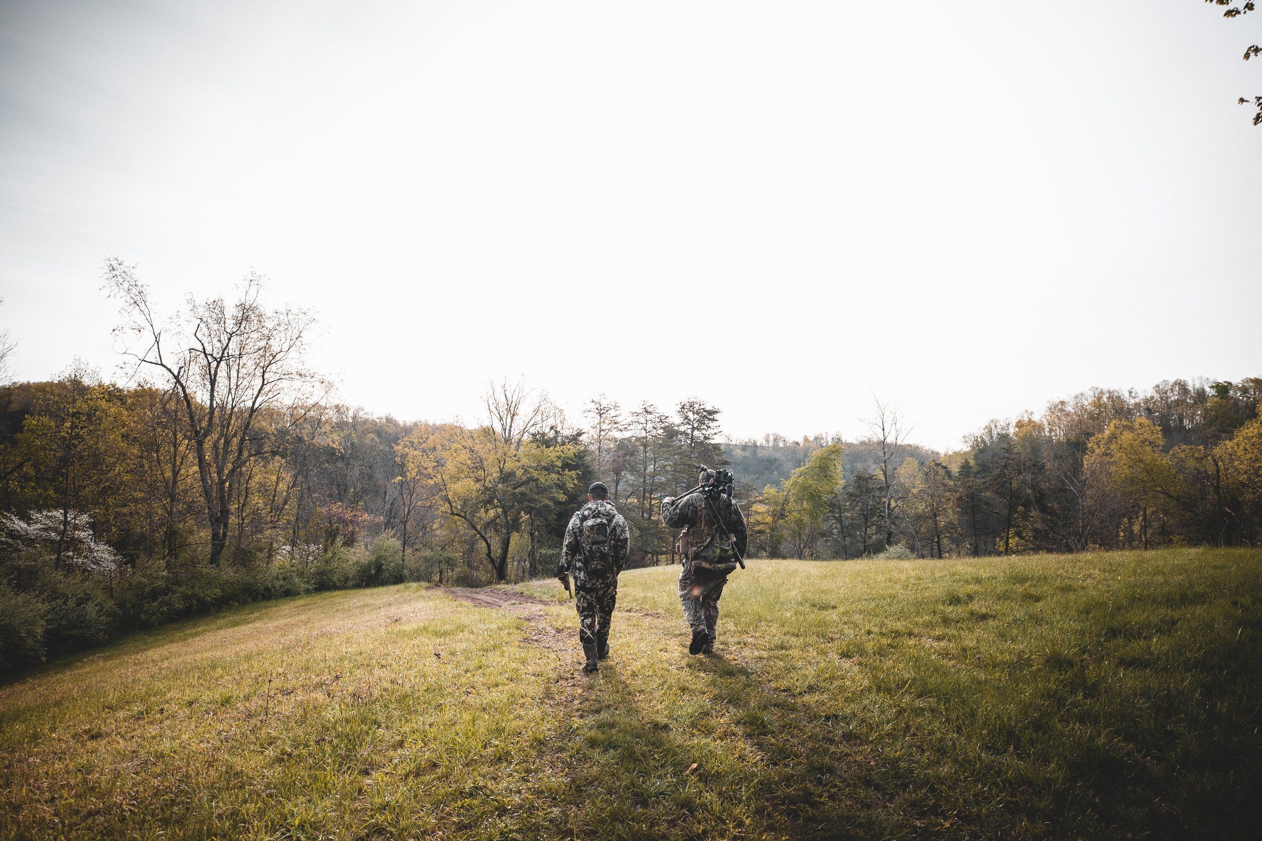 Two hunters with hunting gear walking across a field, axis deer hunting Texas concept.