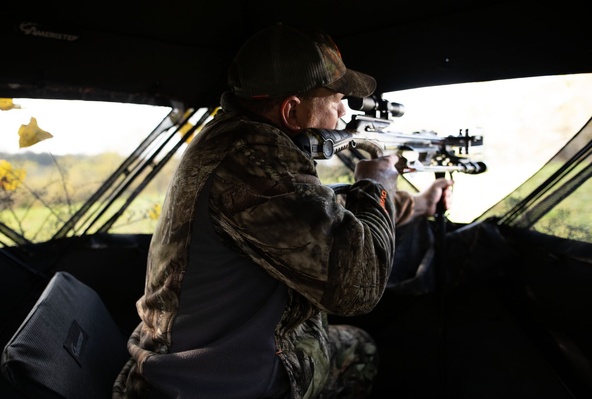 A hunter takes aim while in a ground blind.