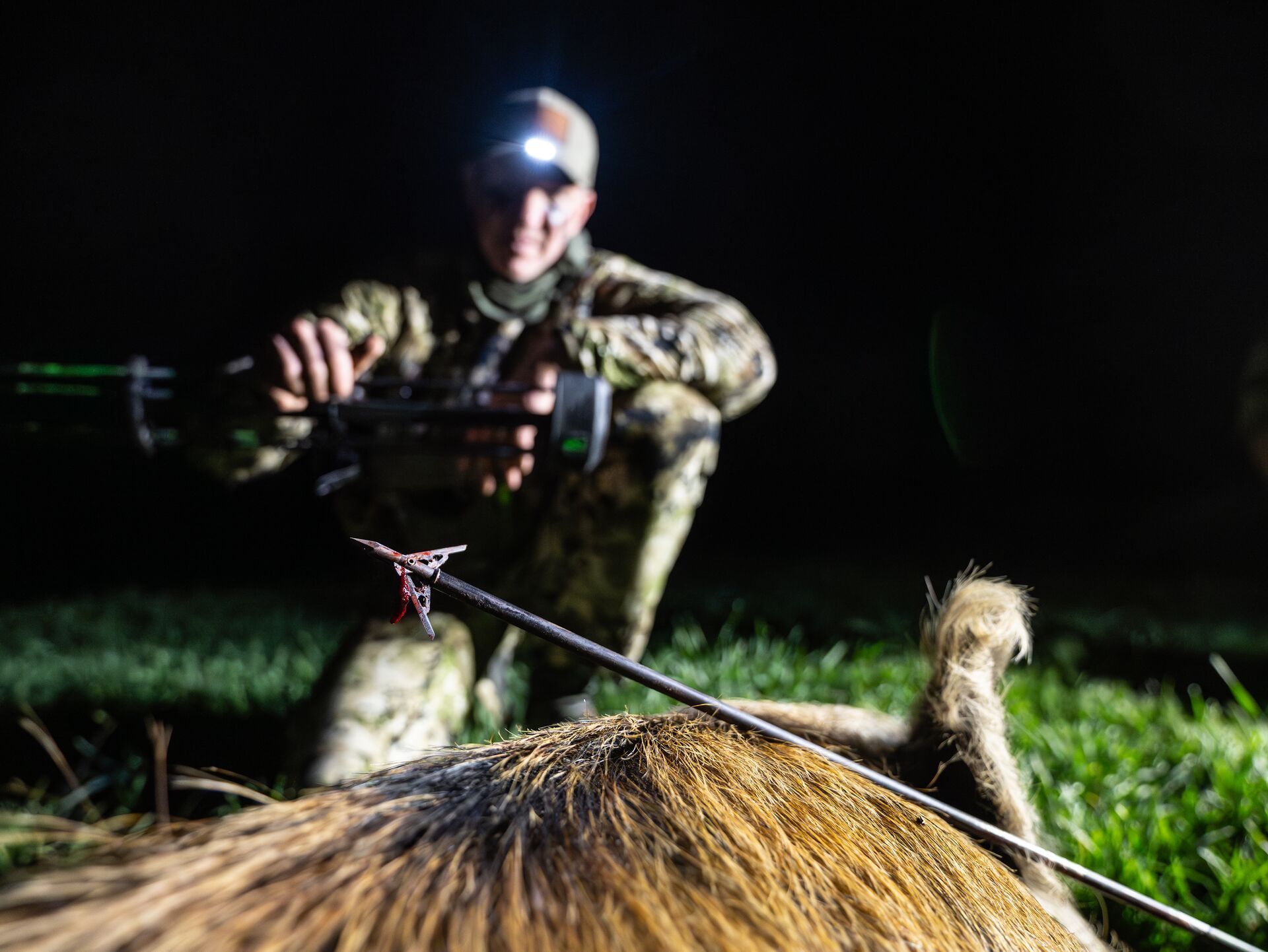 John Dudley blurred behind an in-focus arrow on a big game kill, compound bow hunting concept.