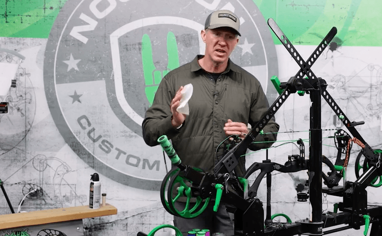 John Dudley using a cloth to wipe moisture from a compound bow.