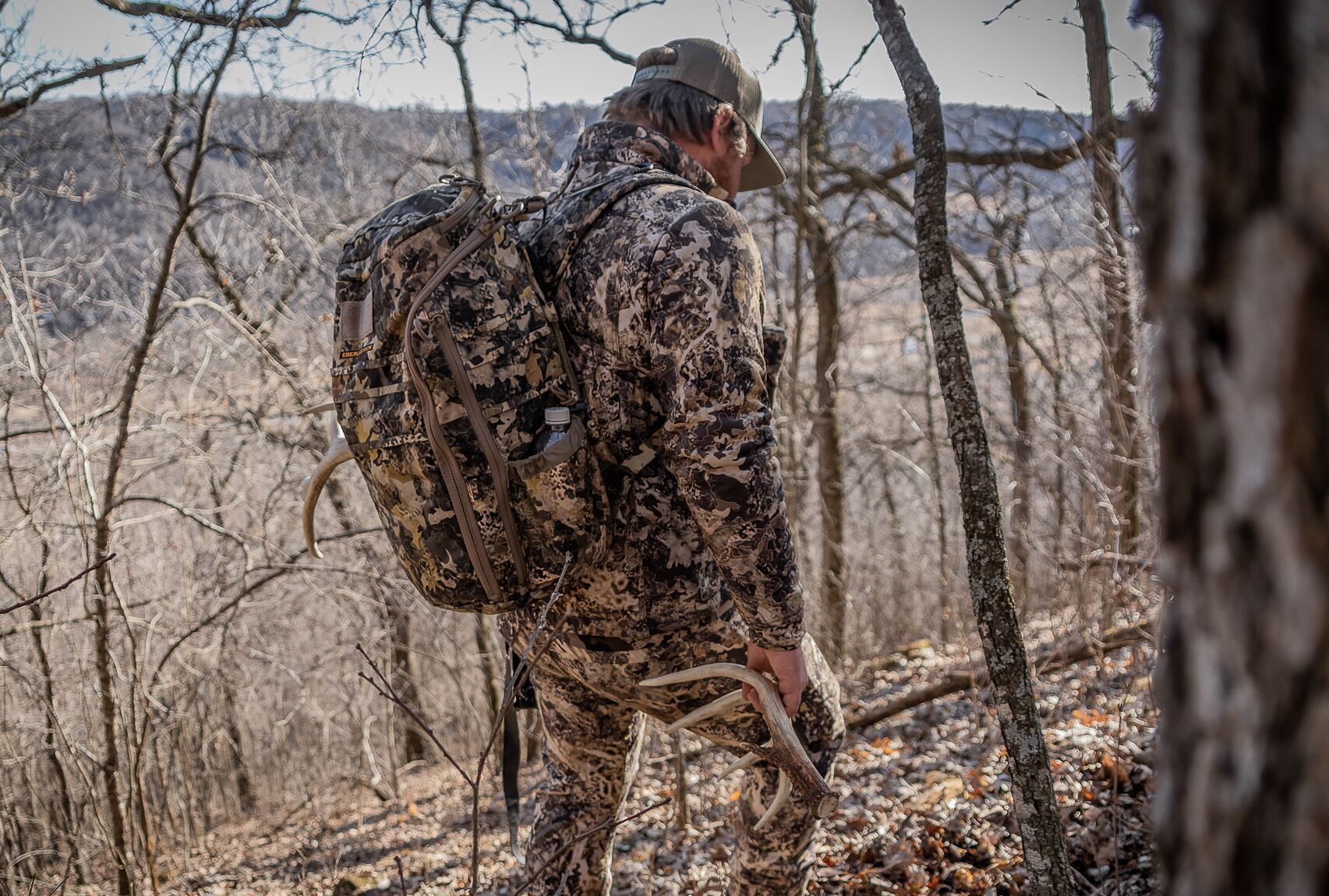 A hunter wearing camo shed hunting in the woods, scouting for hunting concept.