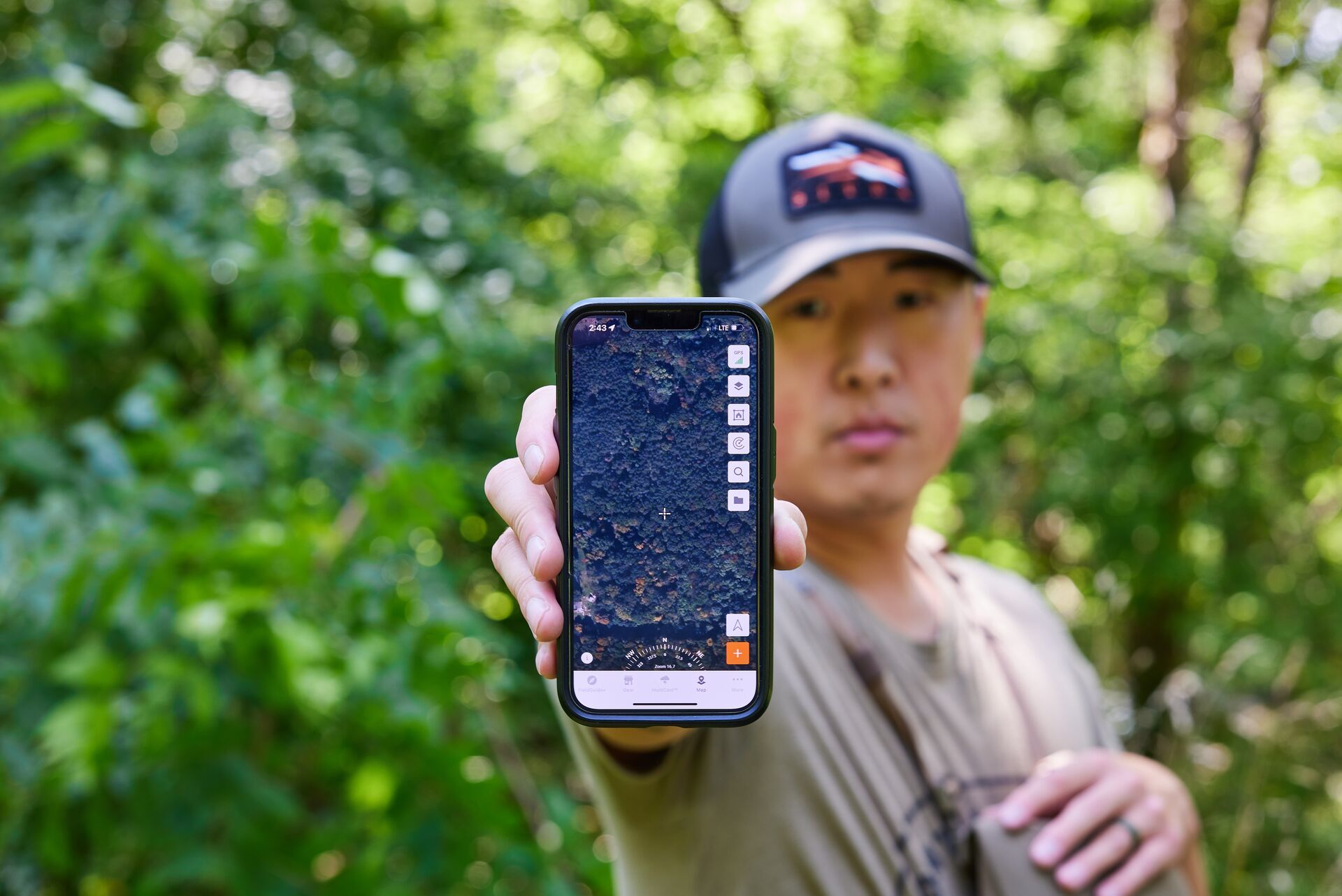 A hunter holds up a cellphone with the HuntWise hunting app on screen, prepare for hunting season concept.