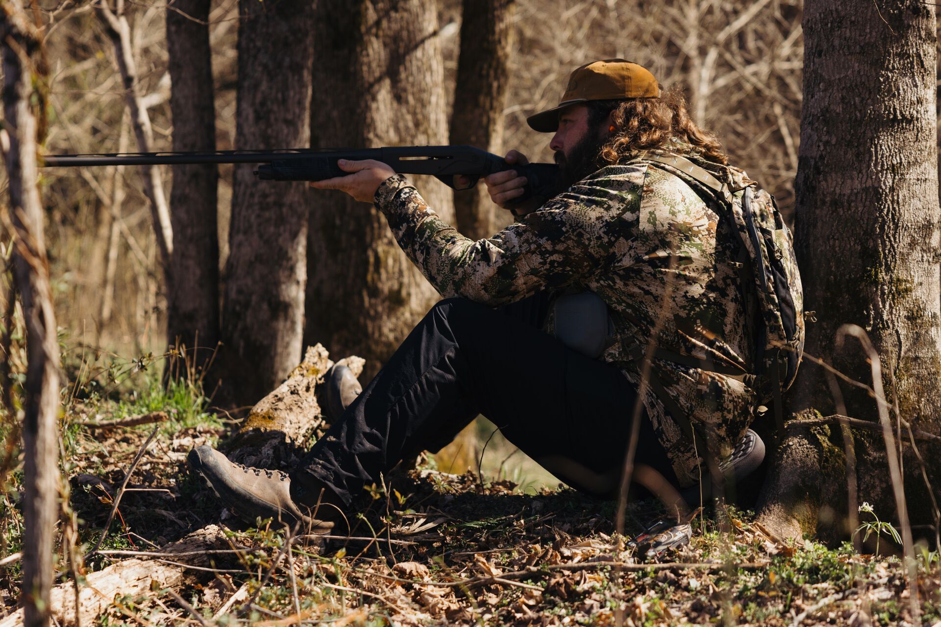 Ben Cole of RootedTV aims a shotgun in the woods, turkey patterning concept.