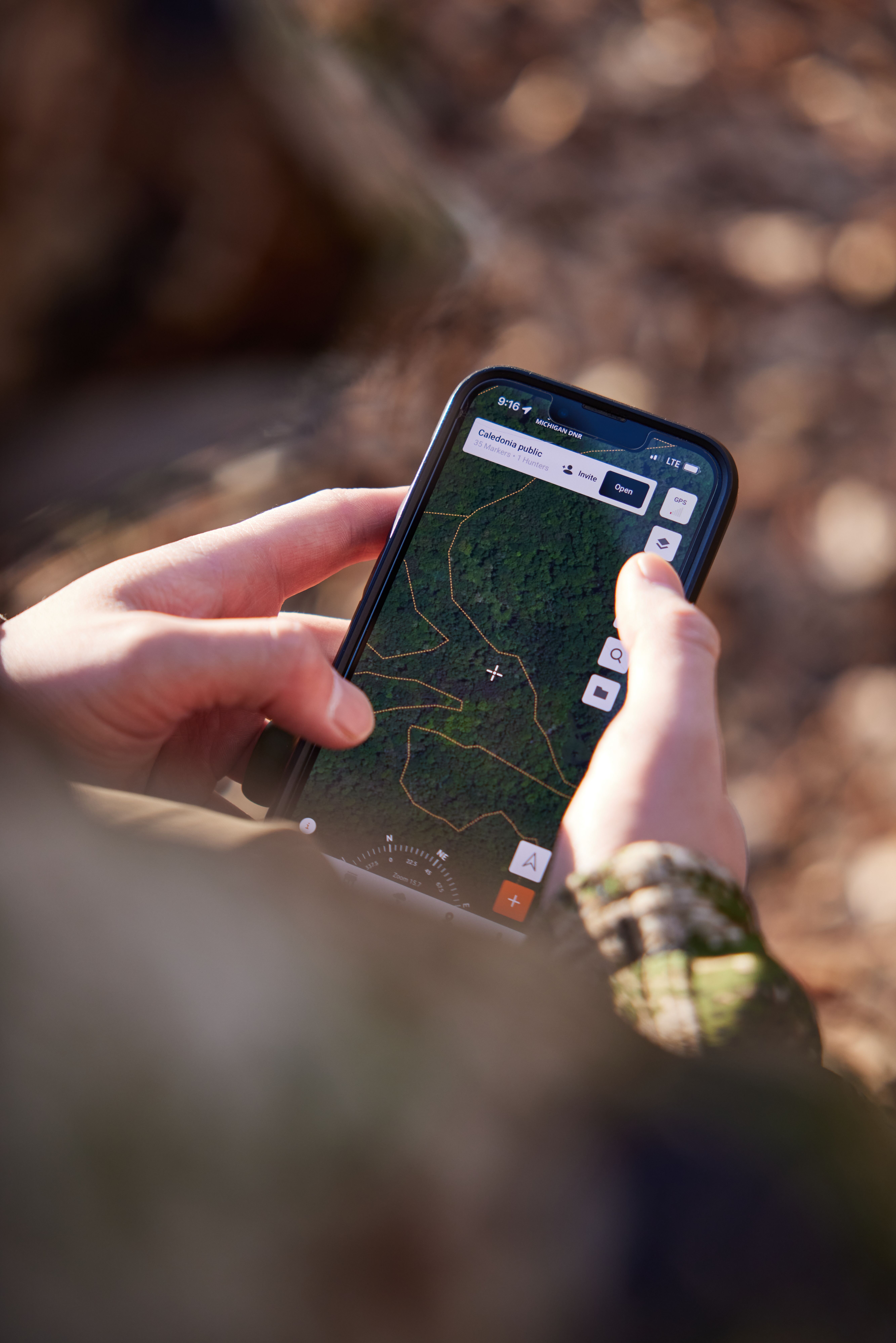 Hands holding a cellphone with HuntWise maps on screen, use HuntWise for muzzleloader hunting season.