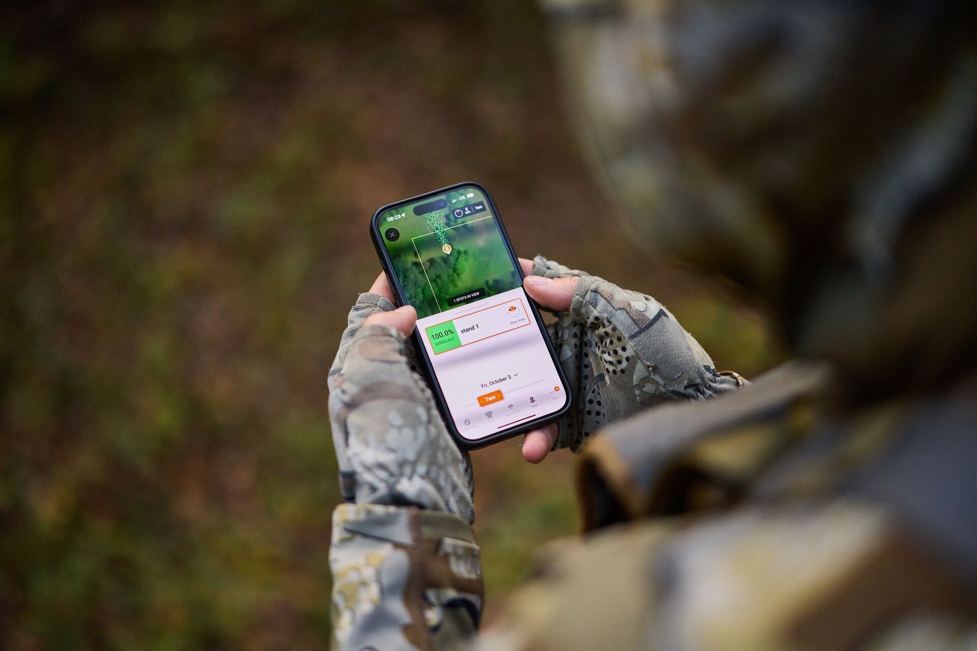 Hunter using phone with HuntWise app on screen during hunt.