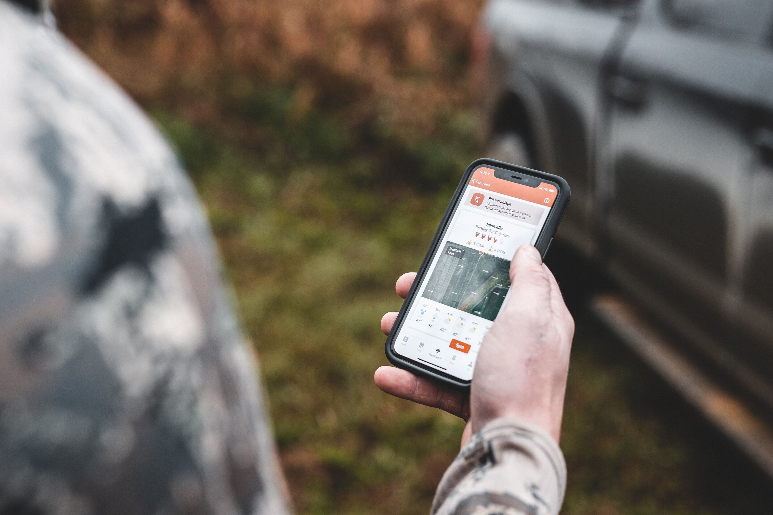Close-up of a hand holding a phone with the HuntWise app on the screen, Coues deer hunting concept.