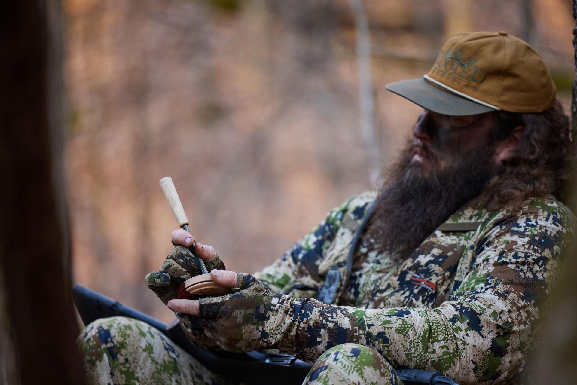 Hunter in the woods using a slate call for hunting turkeys.