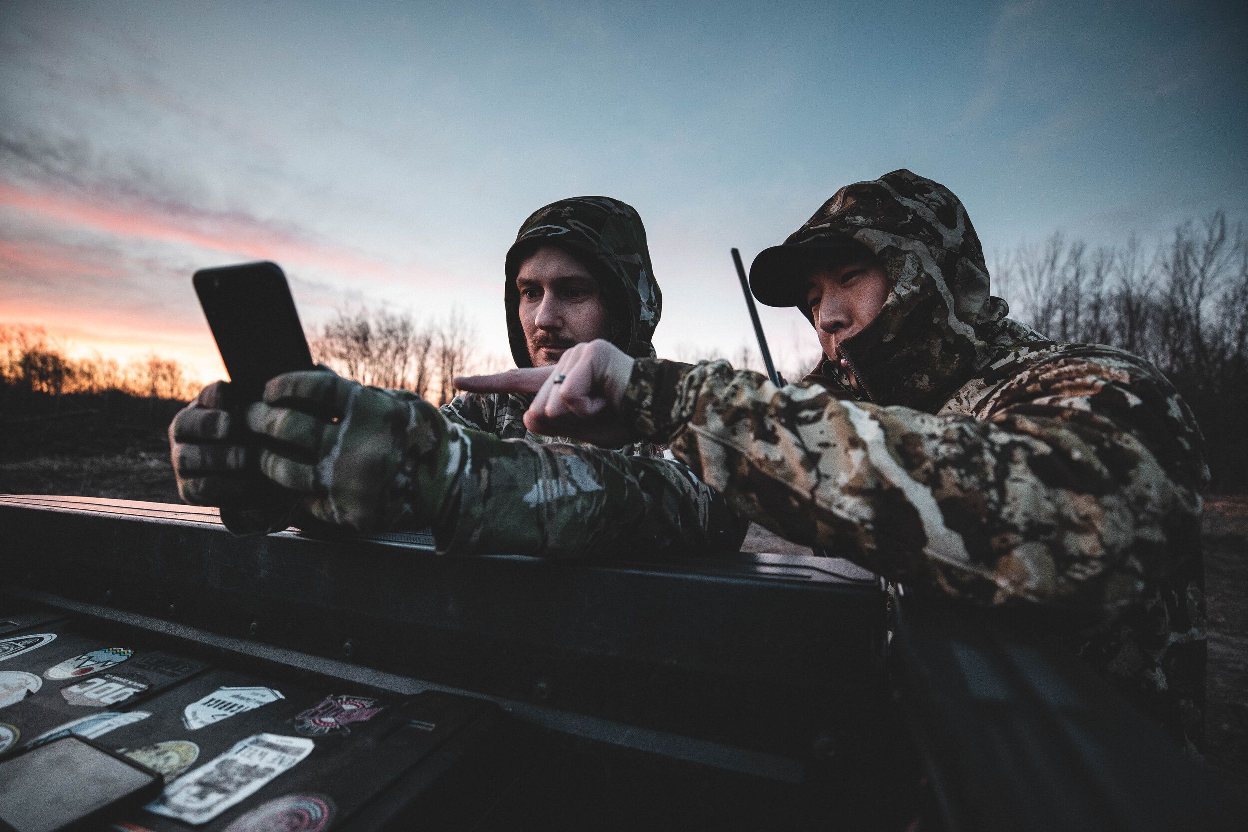 Two hunters look at phone to use HuntWise, are vampire deer real concept.