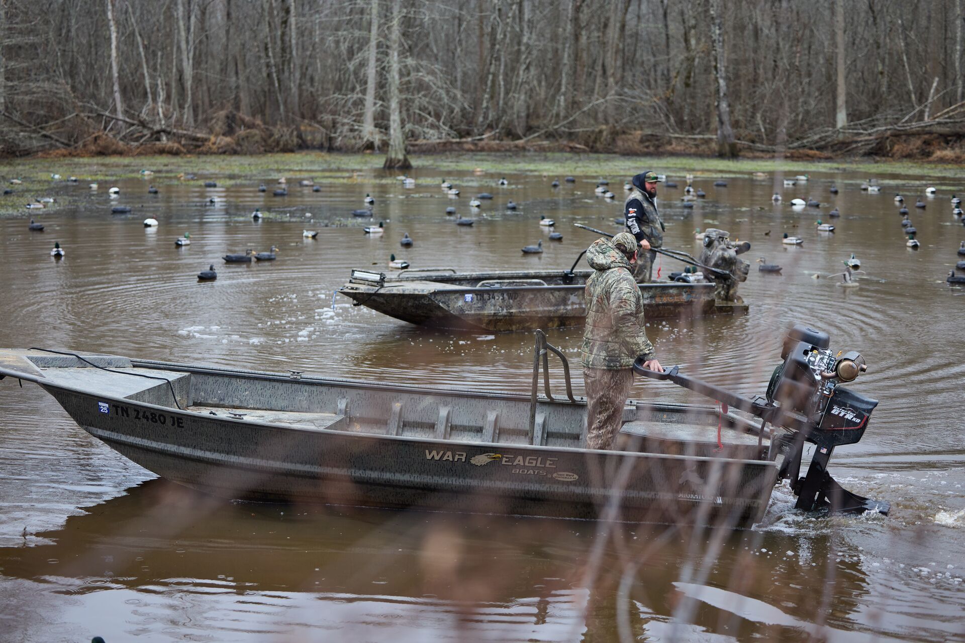 Hunters in boats setting up duck decoy spreads on water.