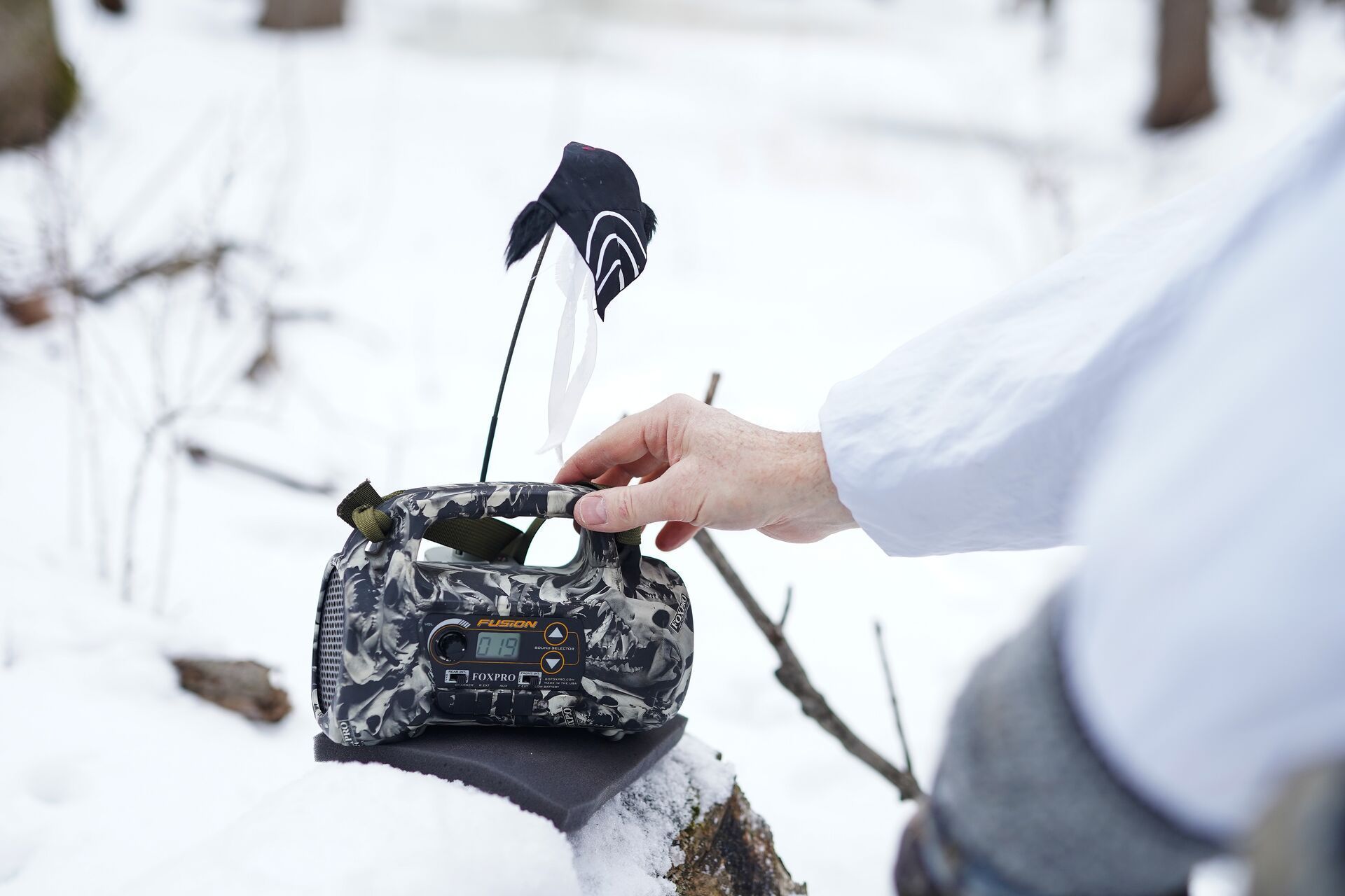 Close-up of an electronic coyote call in the snow, best coyote hunting gear concept.