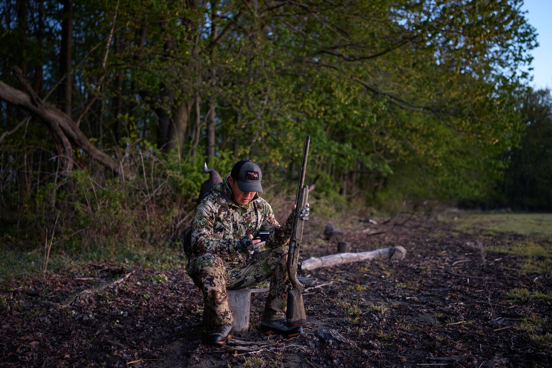Hunter sits and looks at HuntWise on phone during hunt.