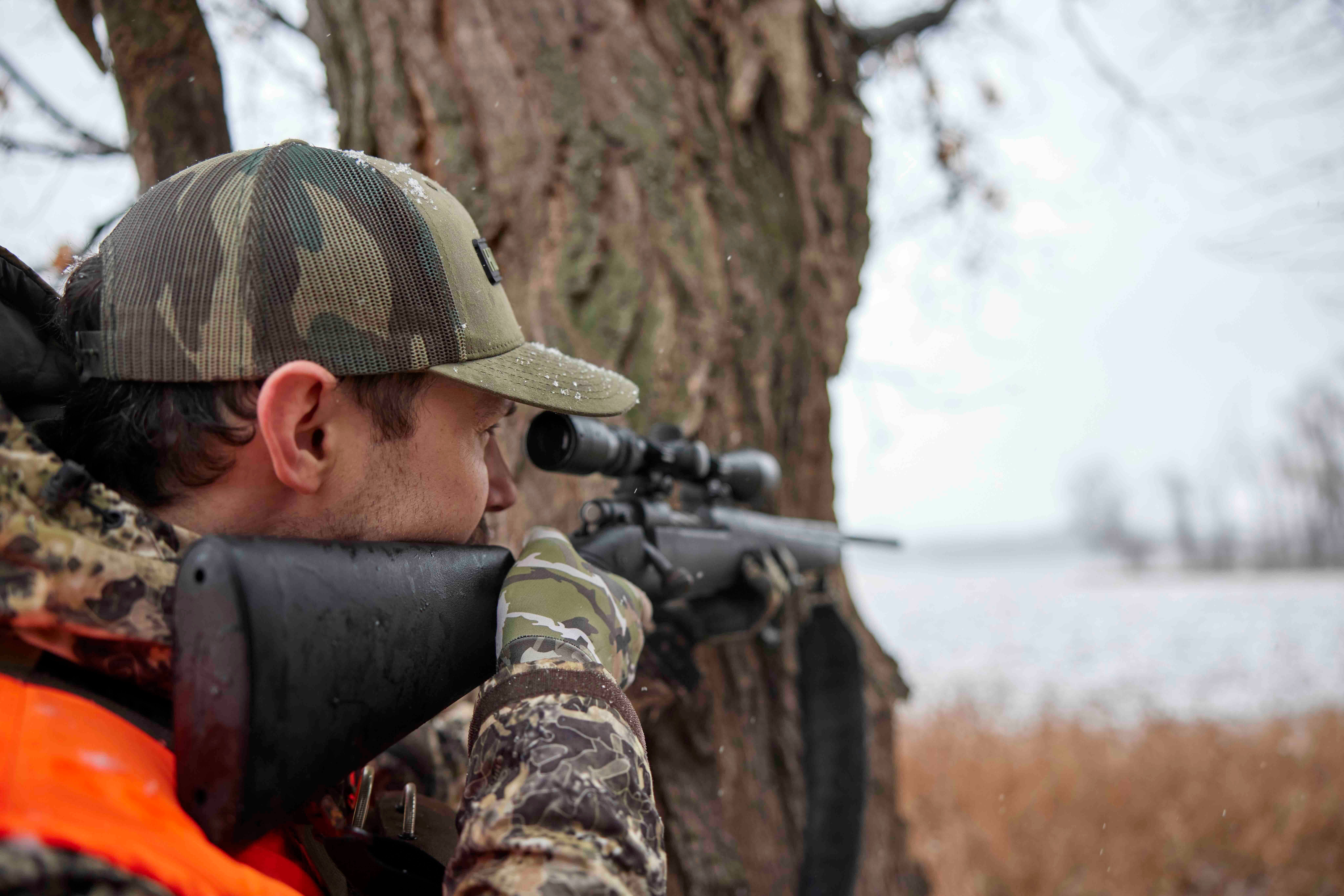 A hunter aims a rifle, understanding sounds deer make concept.