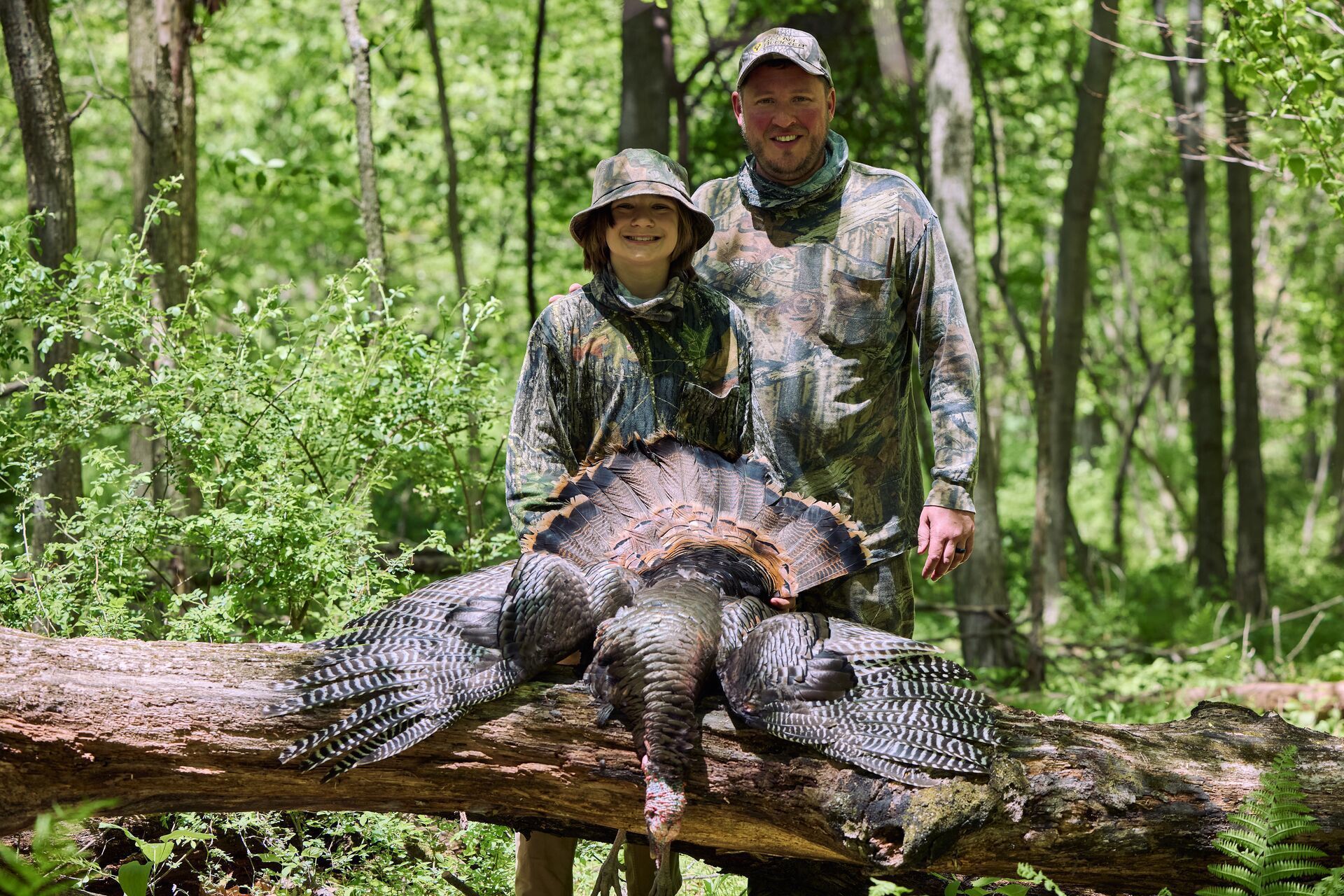 Man and boy smile with turkey after hunt, Indiana turkey hunting concept.