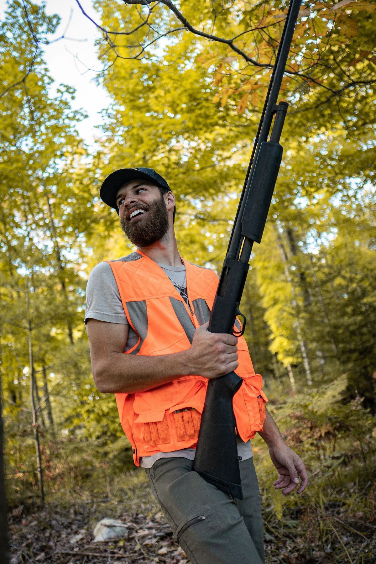 Hunter smiles with shotgun in orange vest, best dove hunting near me concept.