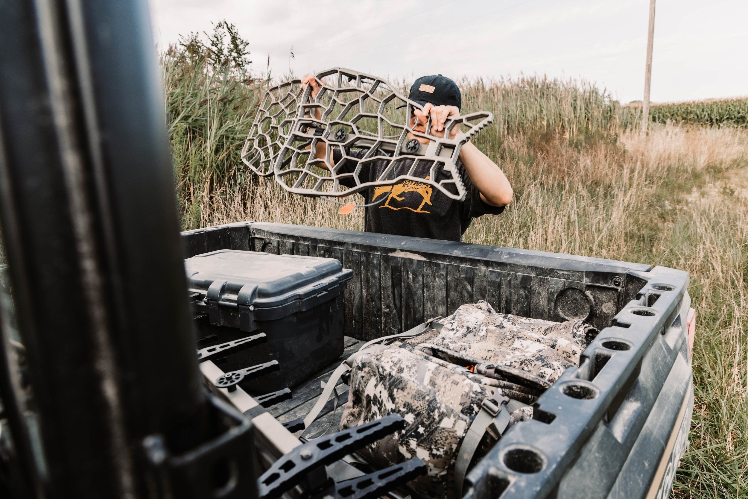 A hunter gets a tree stand from the back of a truck with other gear, hunting deer in Florida concept.