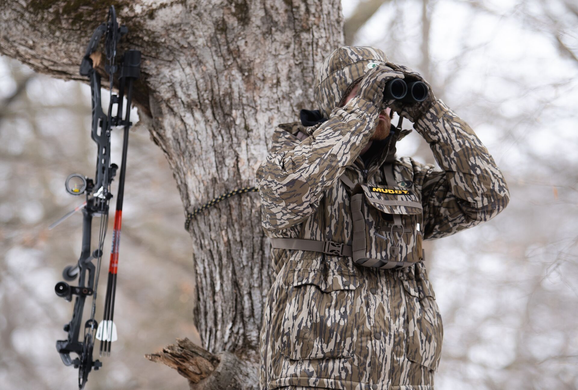 A hunter dressed in camo looks through binoculars, California hunting concept.