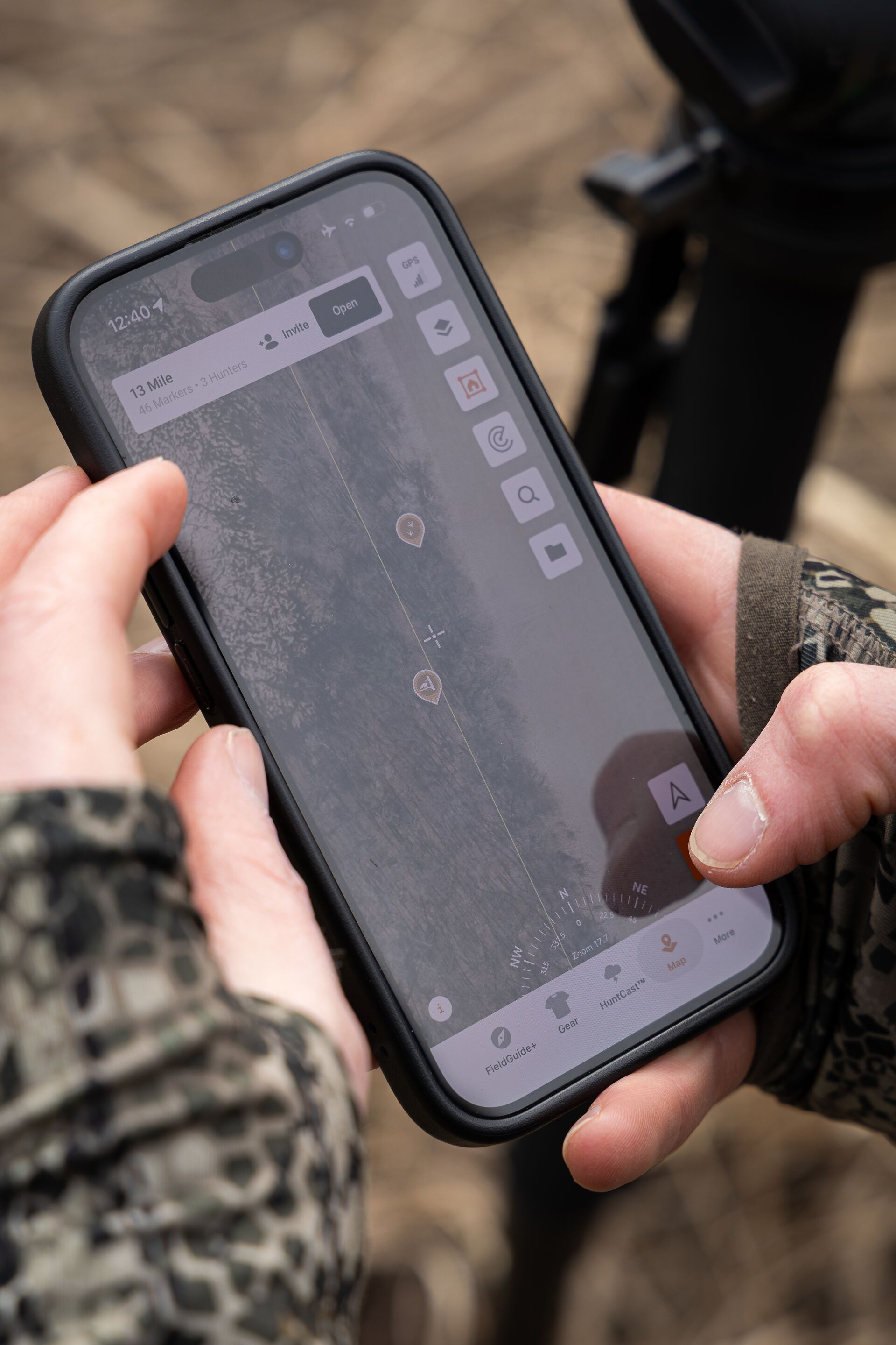 Close up of hands holding phone with HuntWise on screen, mule deer hunting concept.