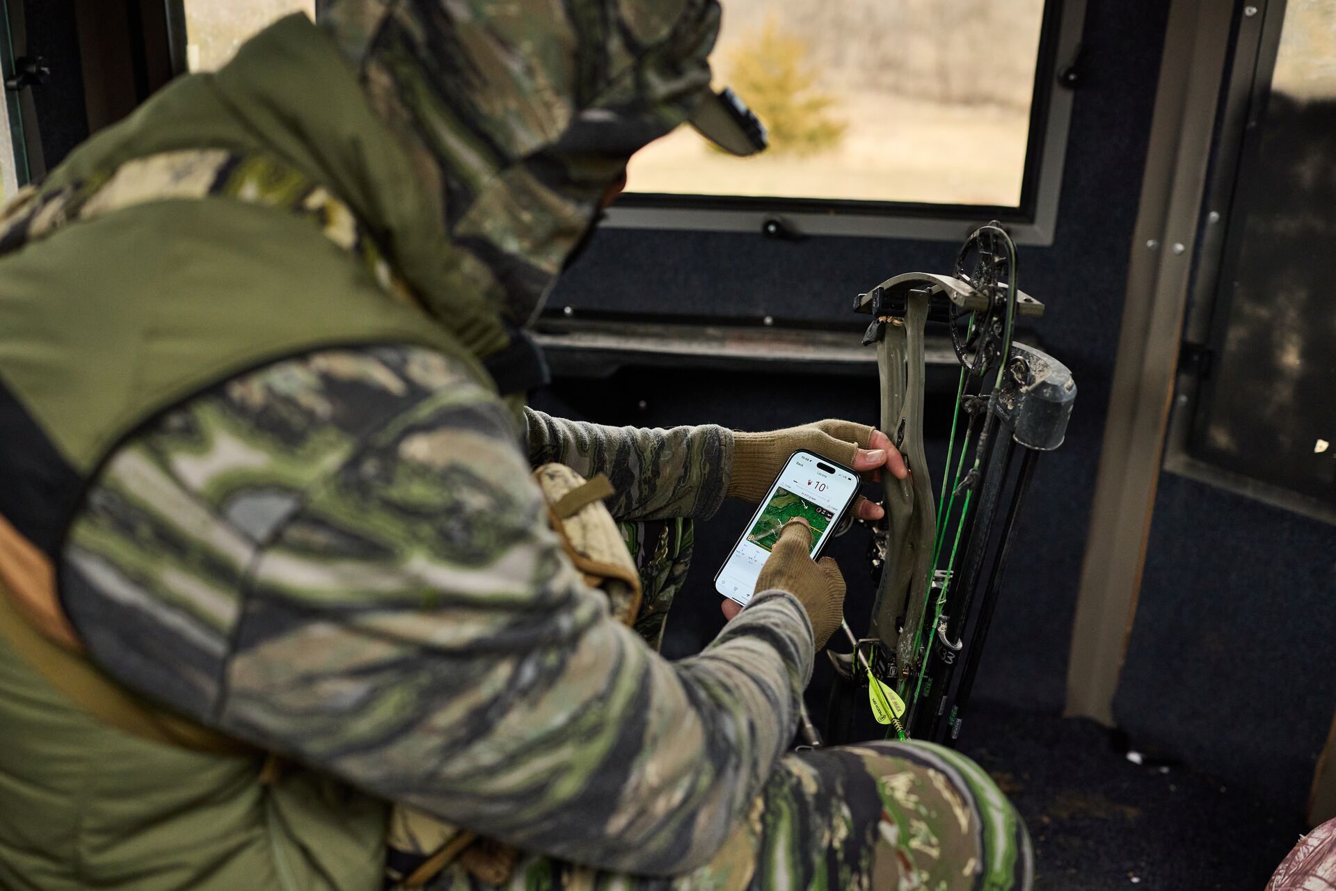 Hunter using HuntWise in a deer blind, where can I go hunting near me concept.