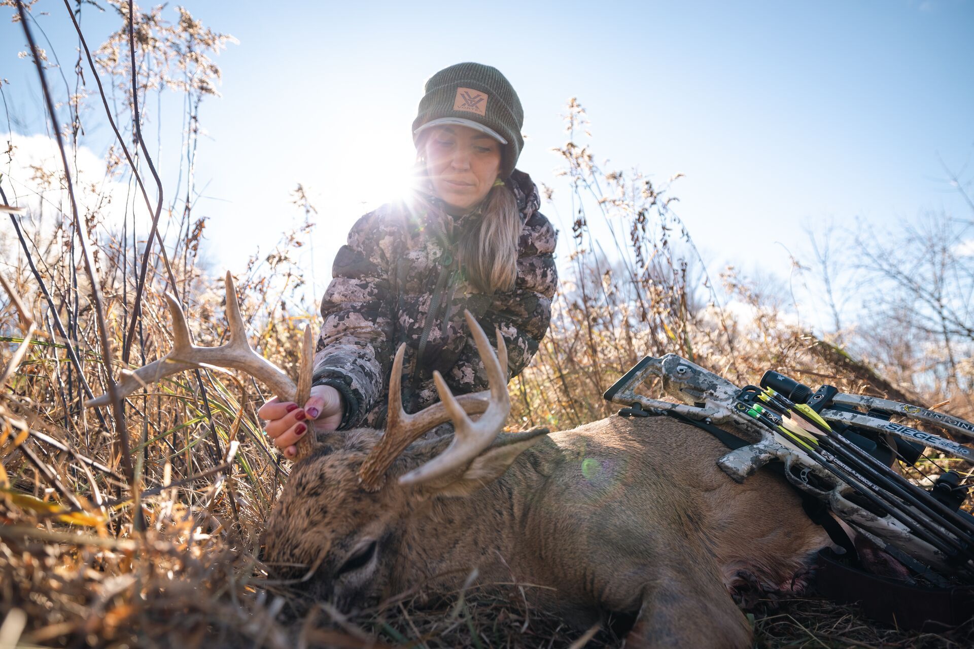 A female hunter holds the antlers of a buck after a deer hunt.