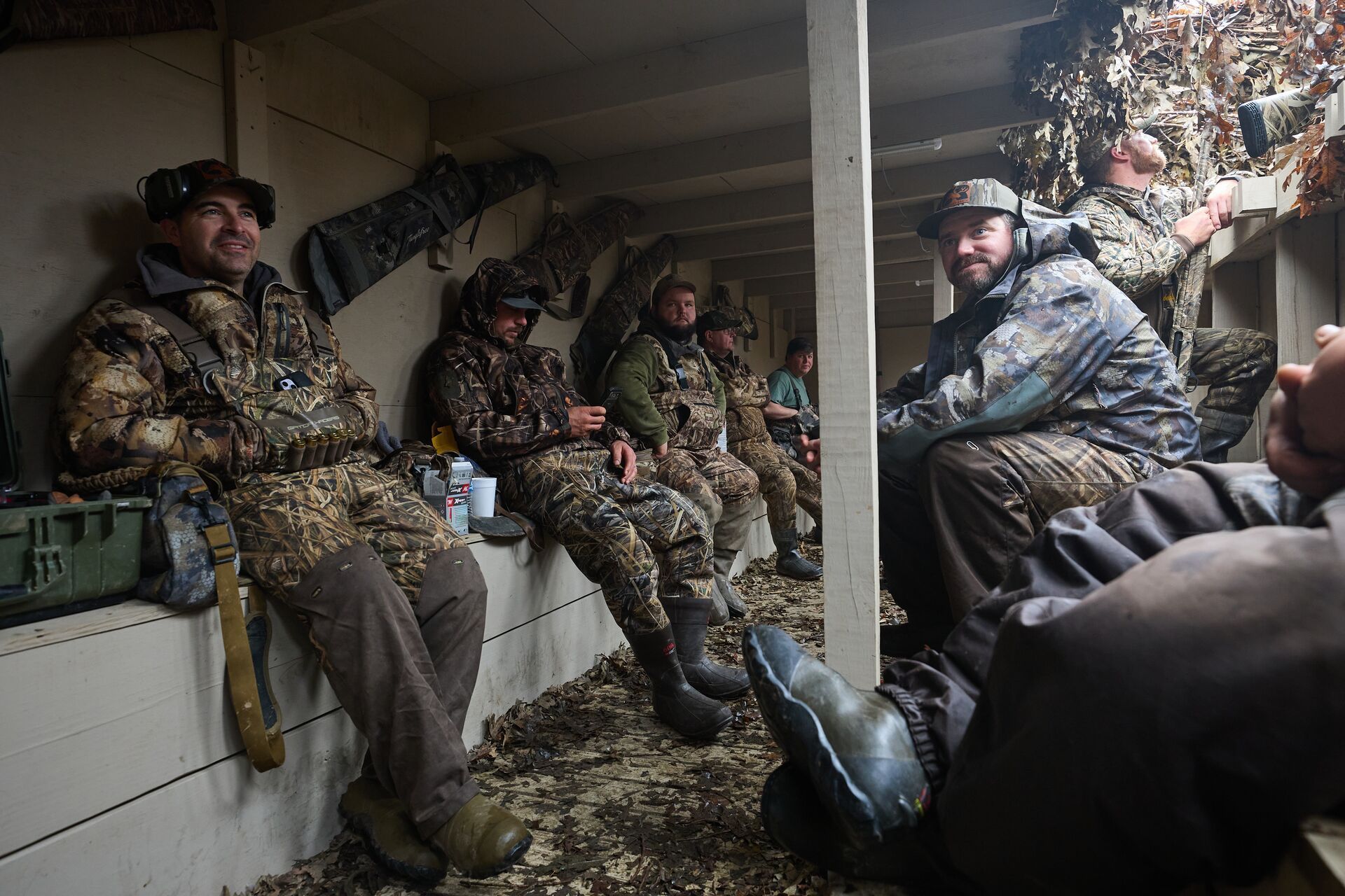 A group of waterfowl hunters sit in a blind, ethics in hunting concept.