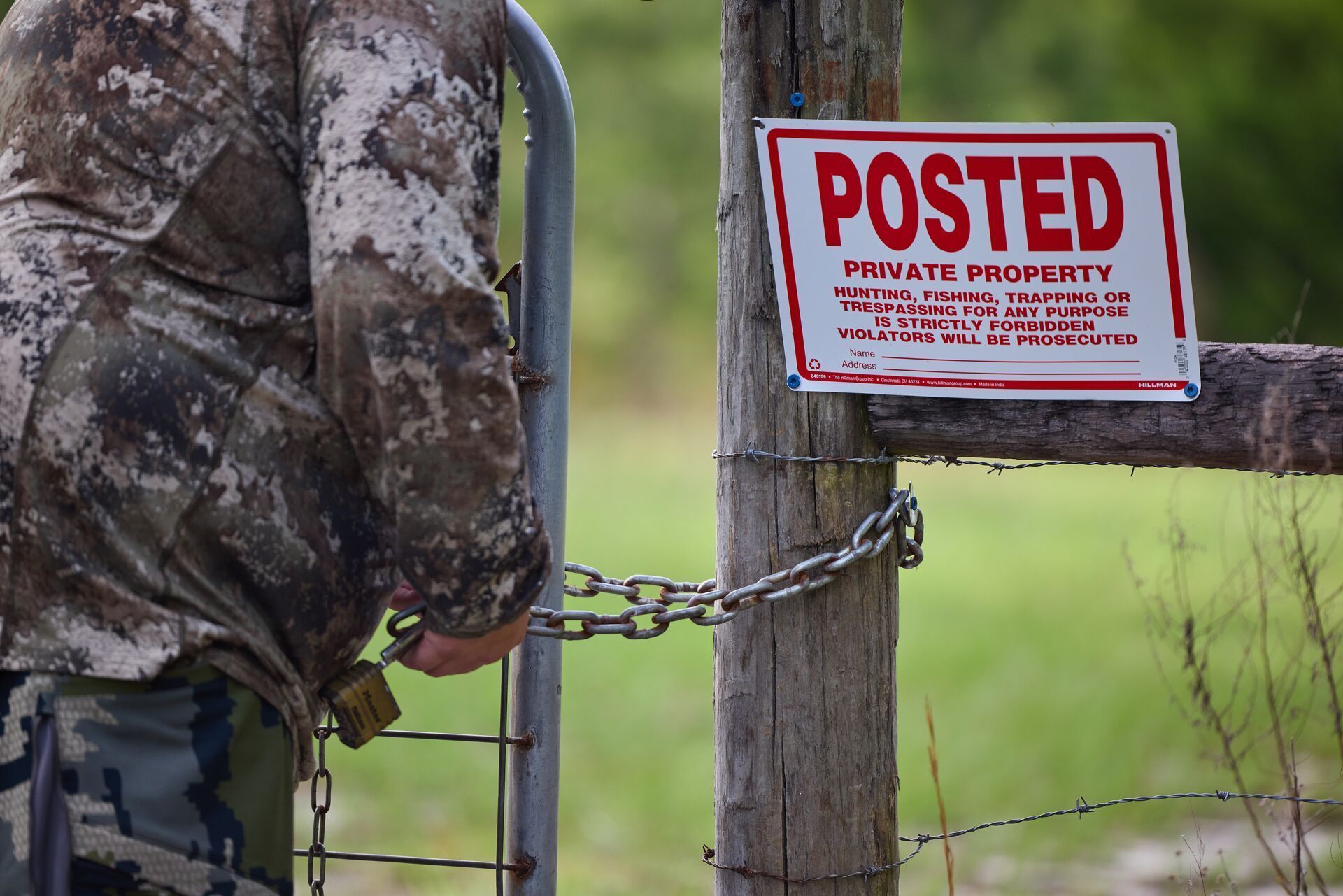 Hunter near private property sign on fence, find land boundaries for hunting.