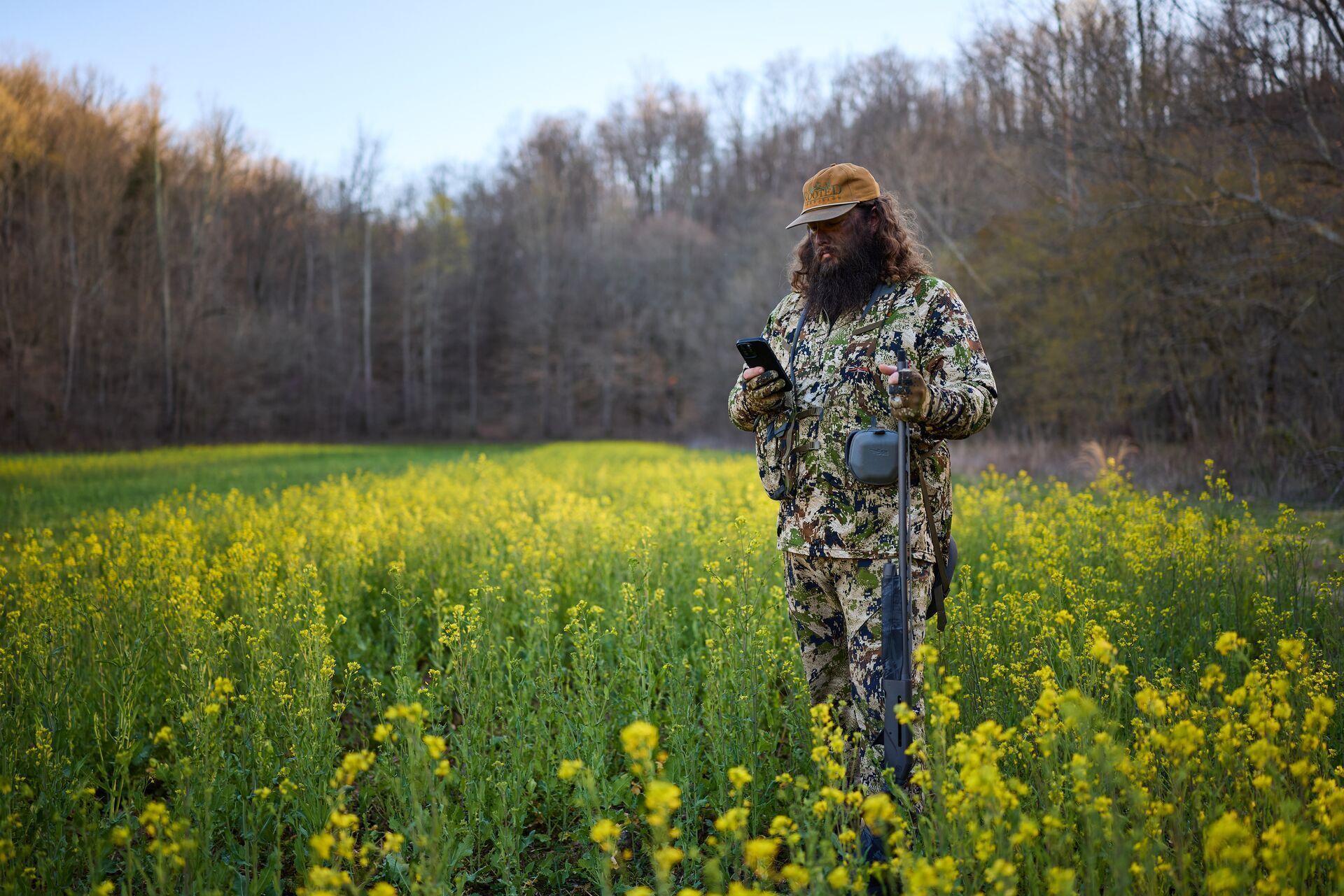 A hunter in a field uses HuntWise on a phone.