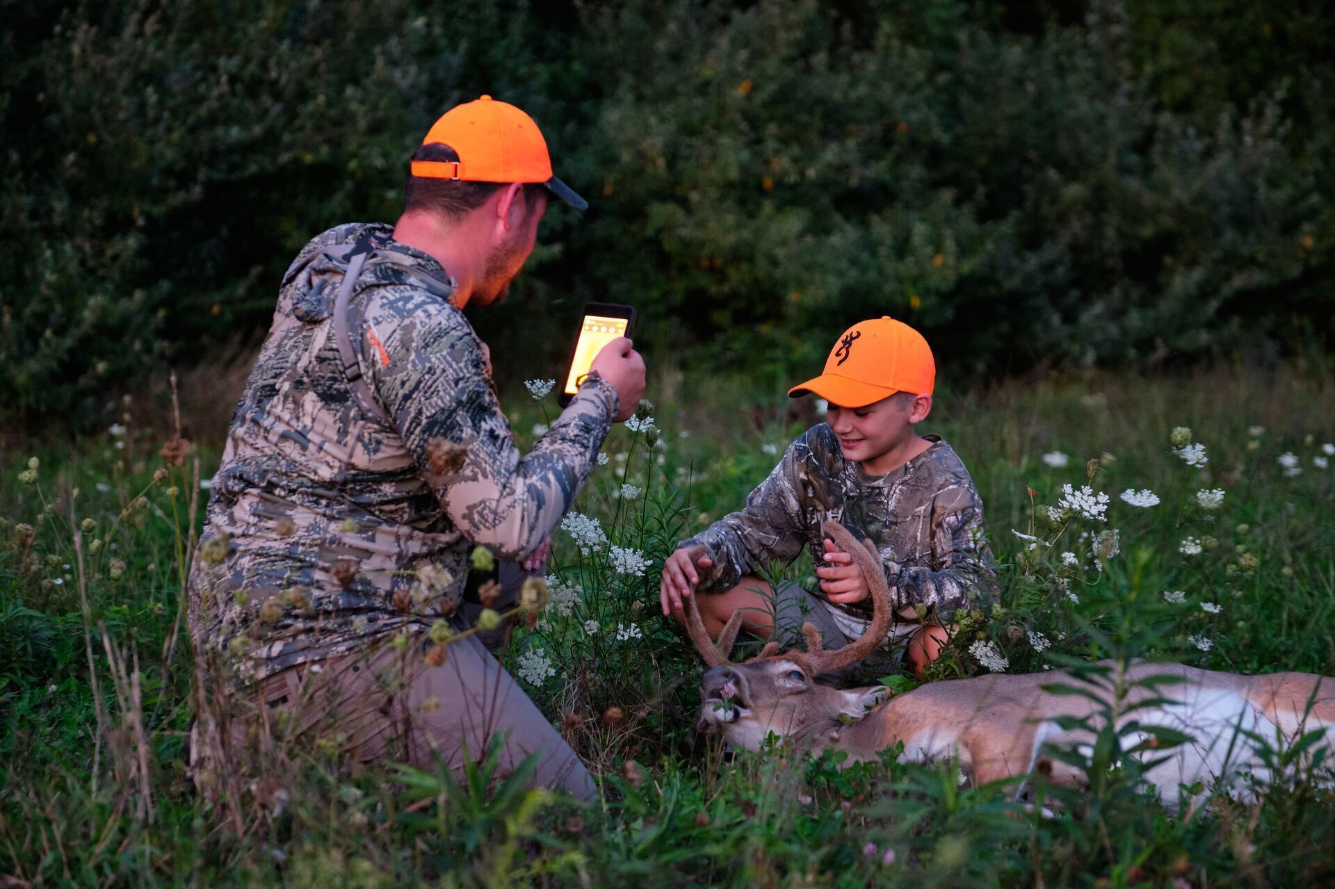 A man takes a photo of his sone with his deer kill, Indiana youth season concept.