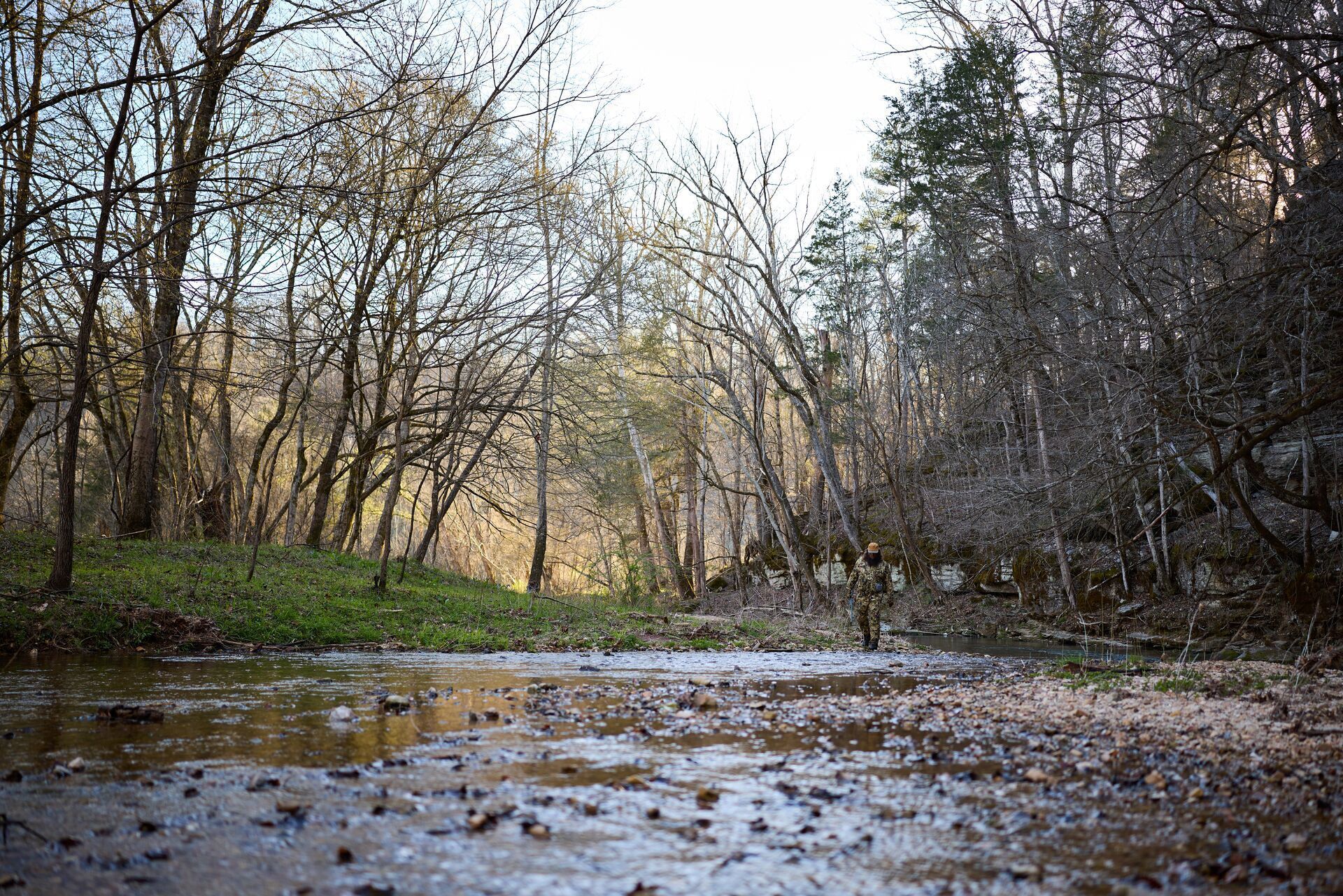 Water running through the woods, hunter down stream.