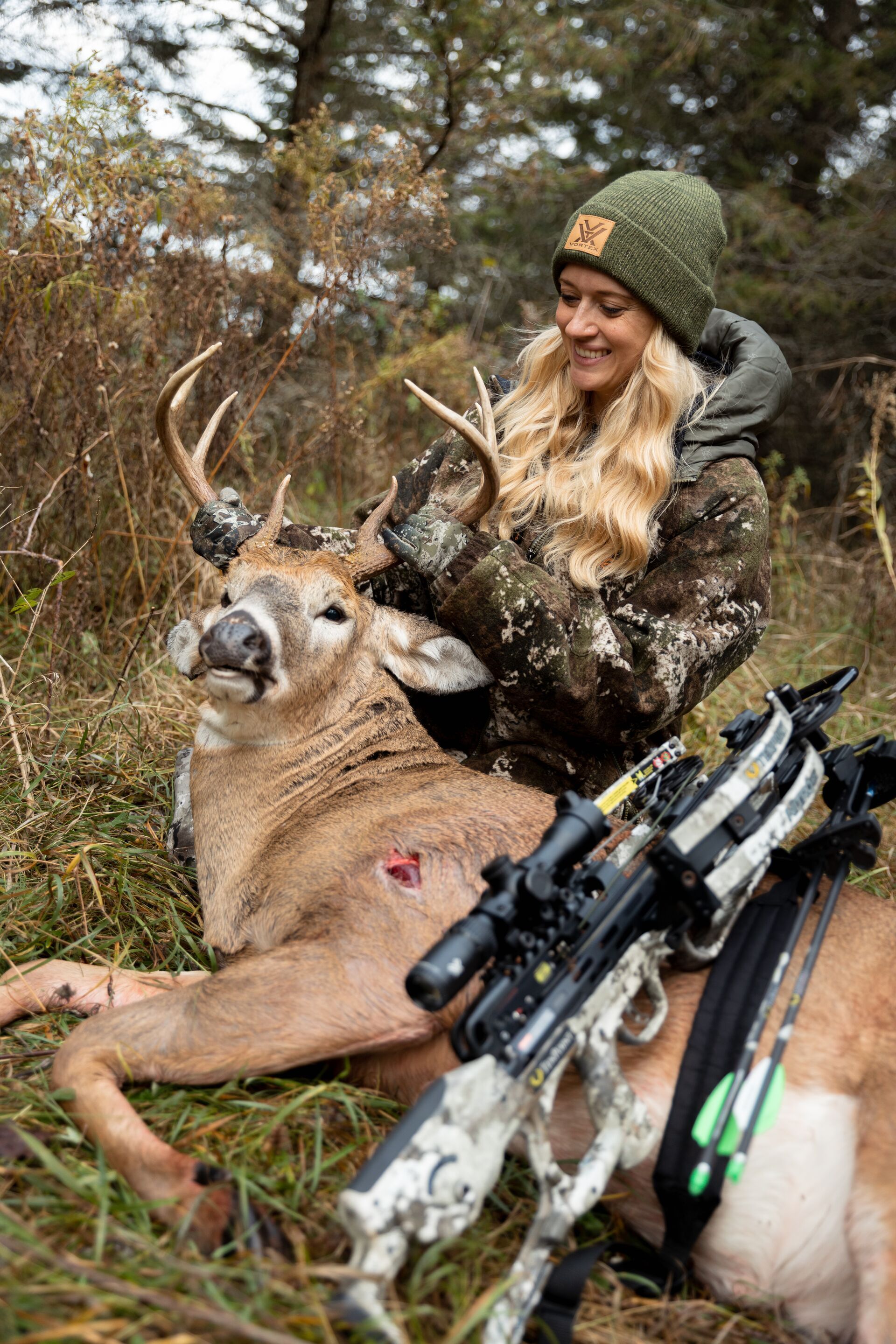 A female hunter poses with her buck kill after a hunt, track deer movement during the rut concept.