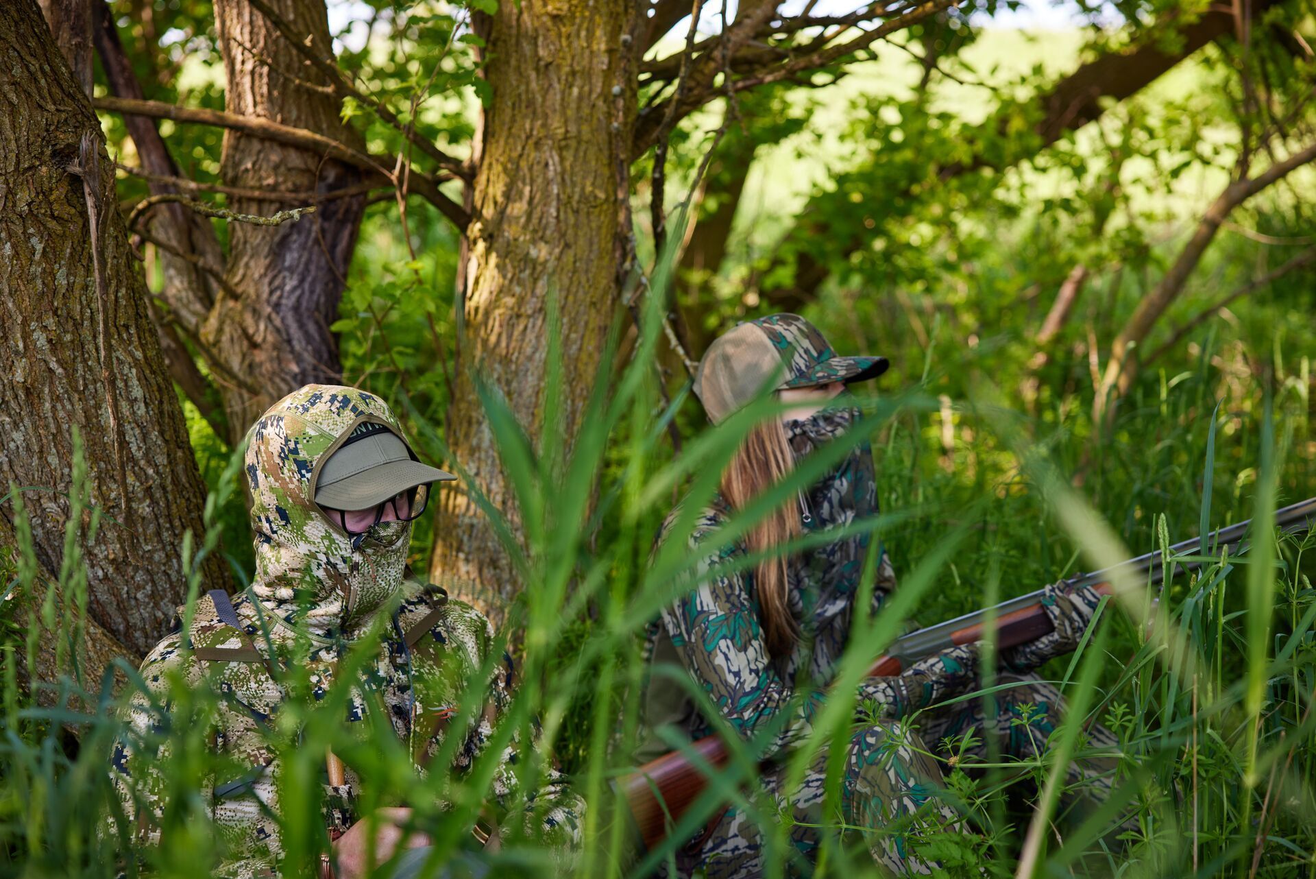 A man and woman in camo hidden in the brush, Minnesota hunting concept.