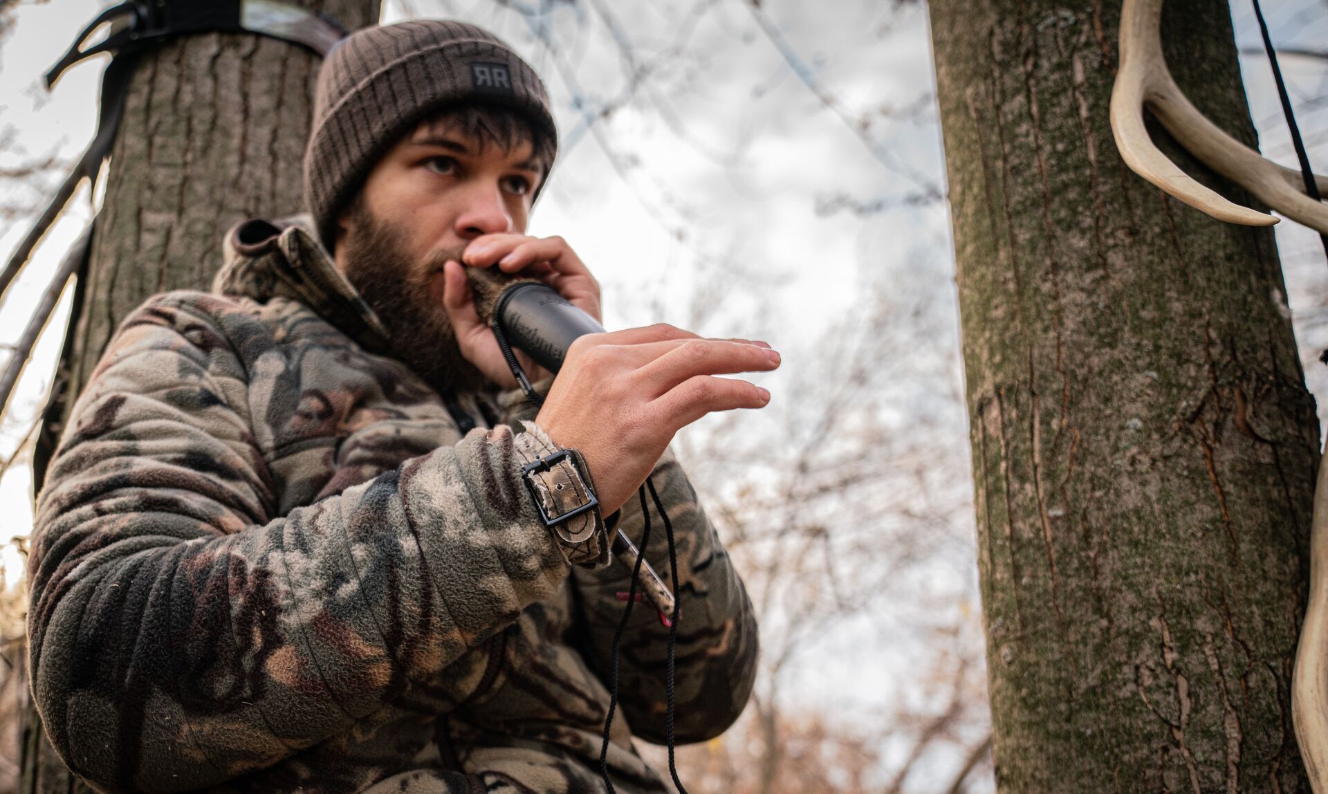Hunter using deer call in the woods, how to call in bucks during the rut concept.