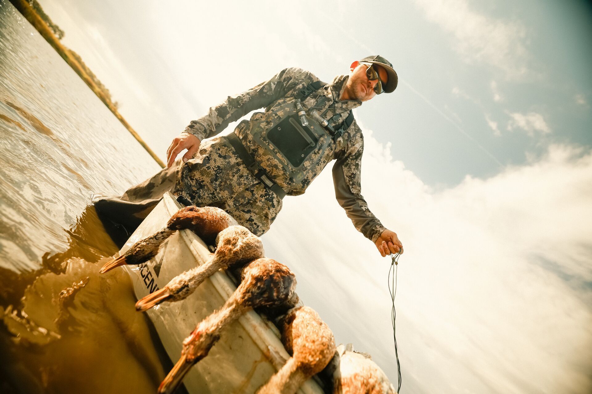 A hunter next to a canoe with a waterfowl harvest after a hunt.