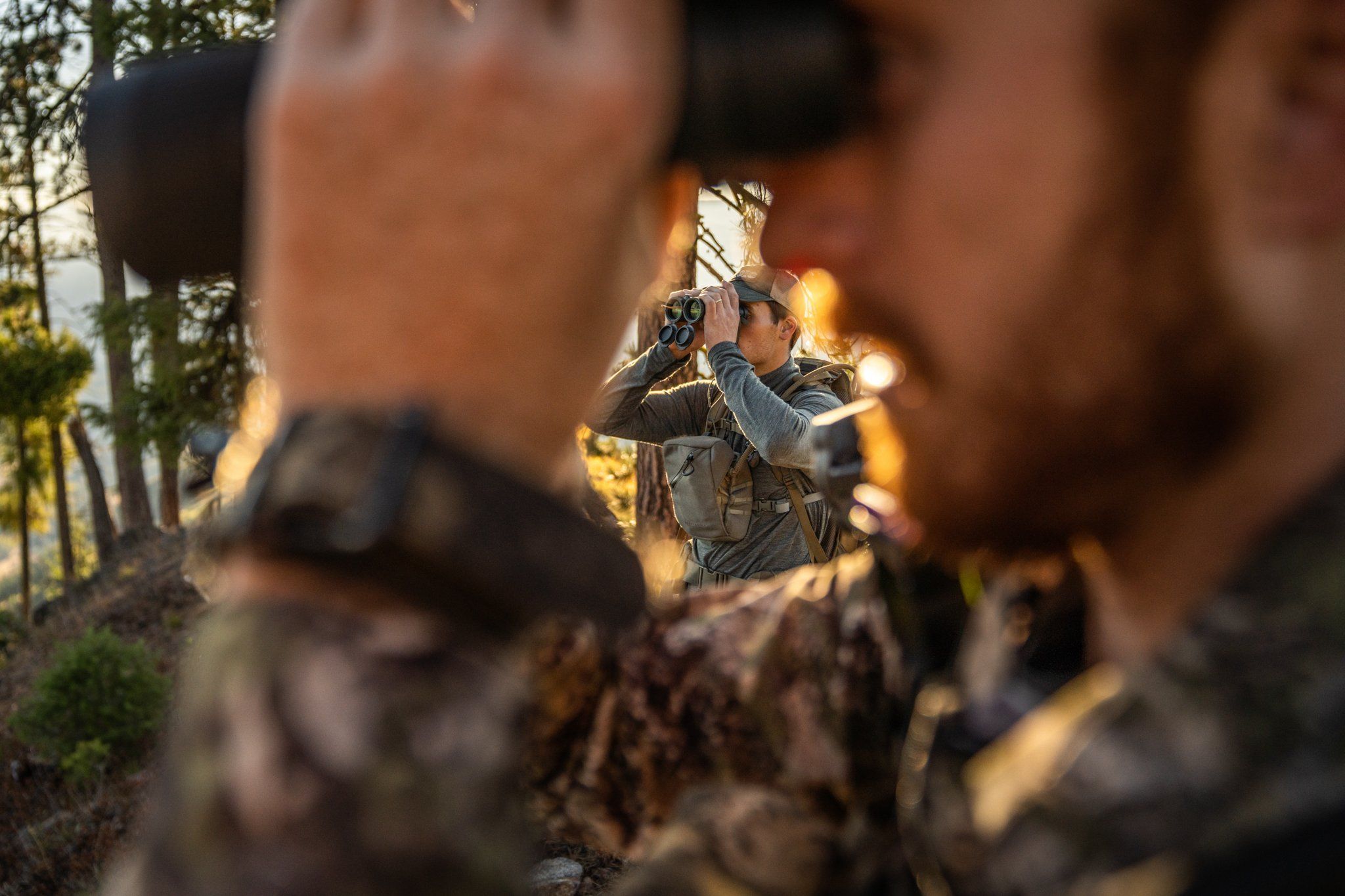 Close-up of hunters using binoculars, scout for Coues deer concept.