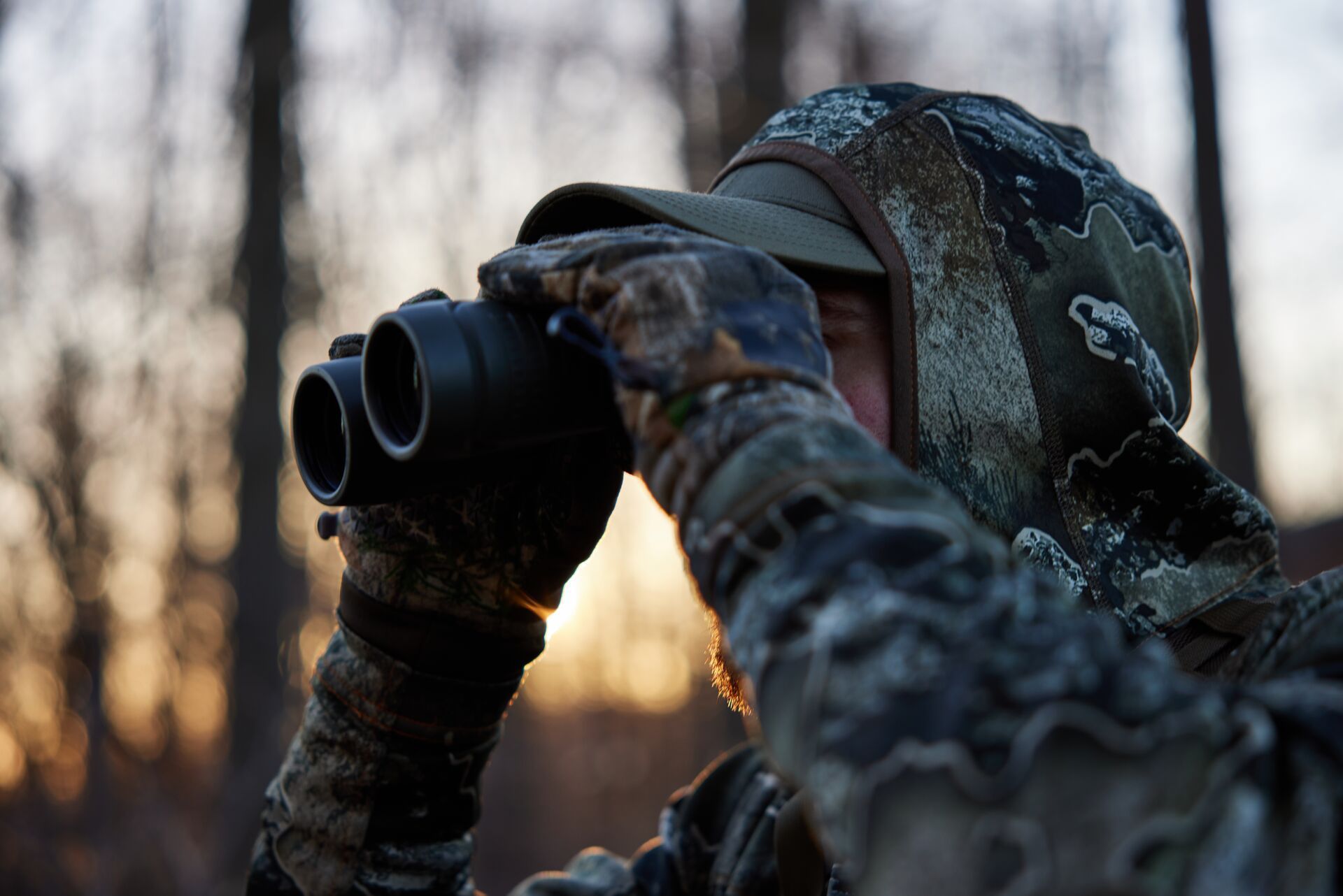 A hunter uses binoculars, glassing and stalking whitetail concept.