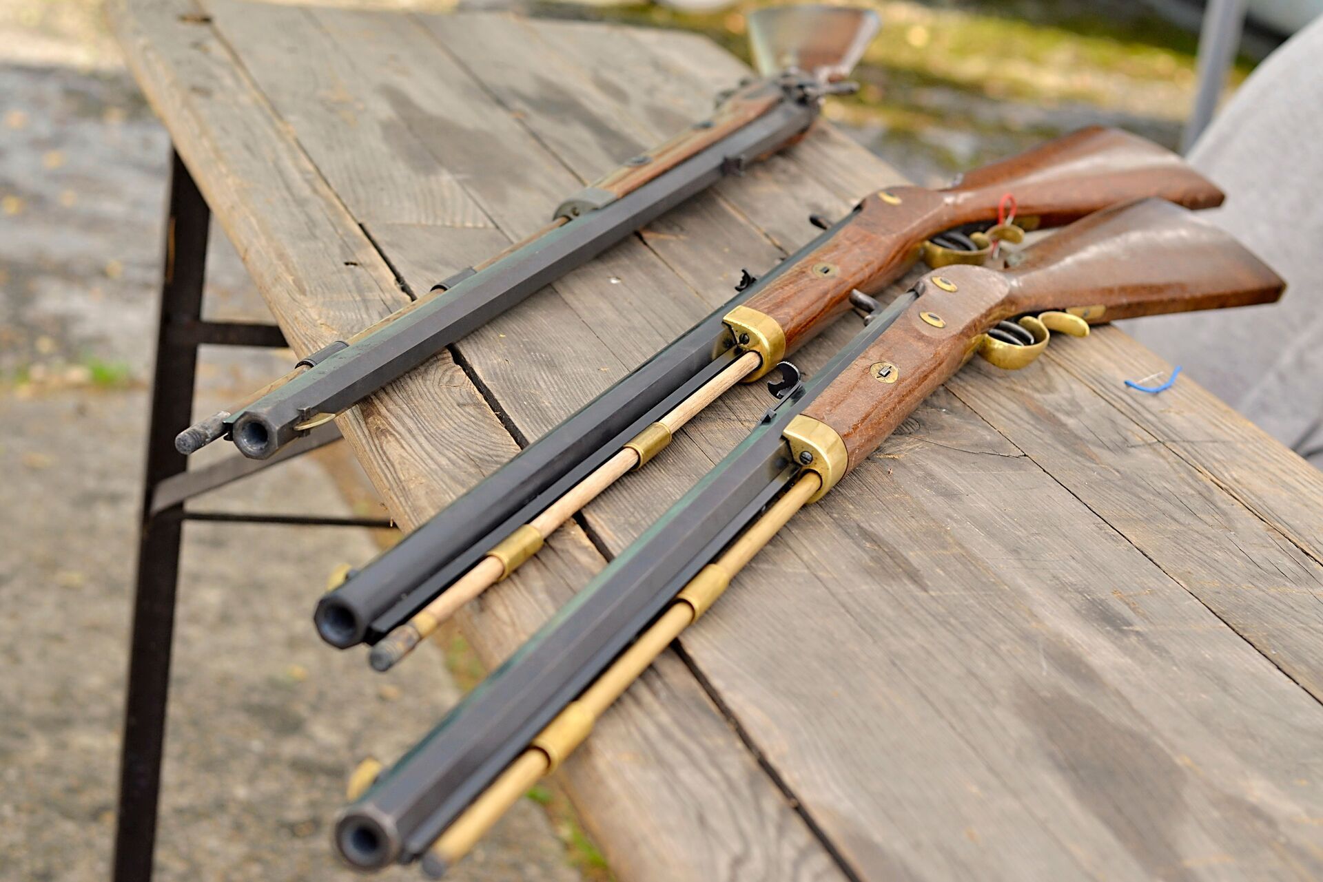 A few muzzleloader firearms laying on a table.