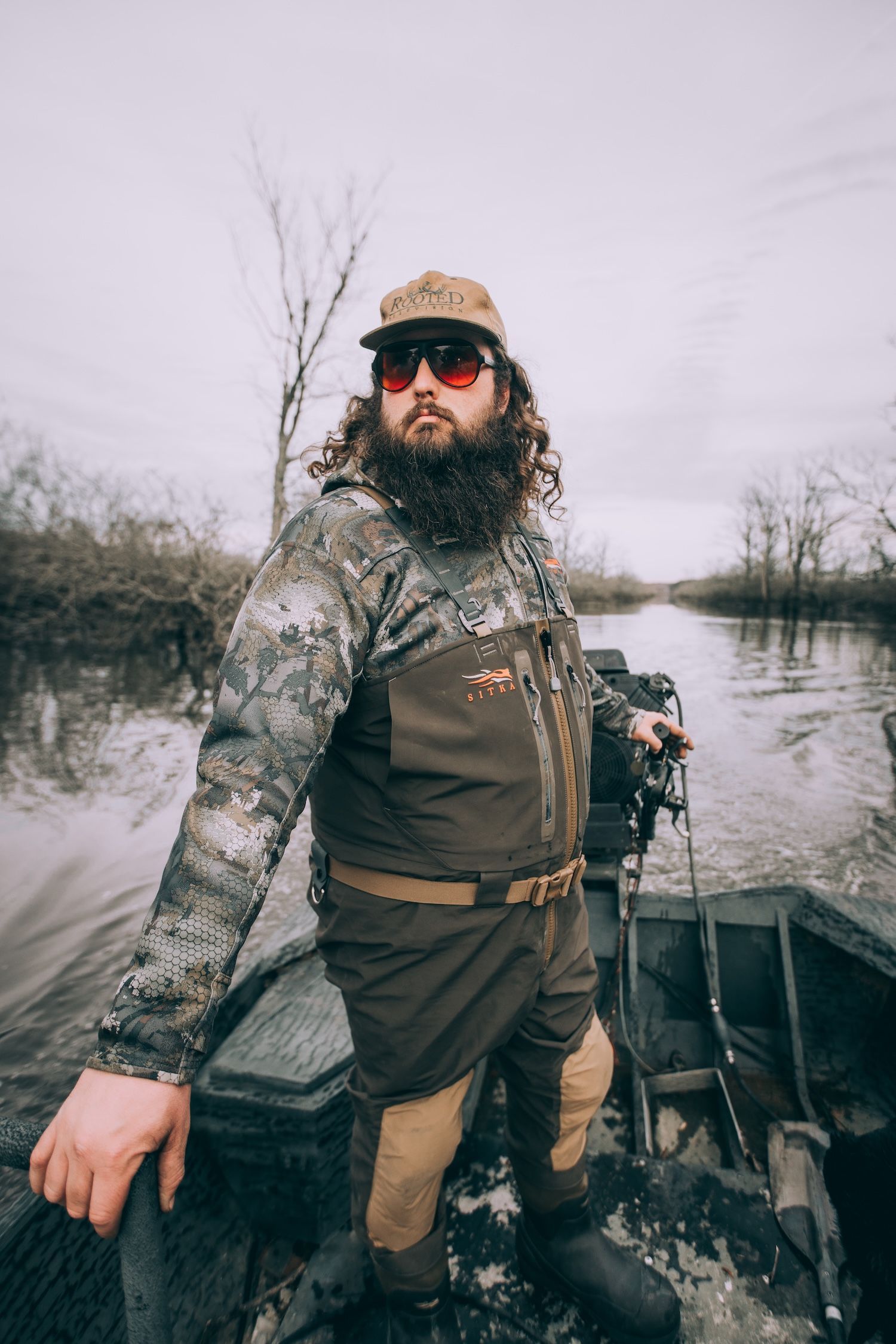 Ben Cole of RootedTV in waders while in a boat for waterfowl hunting tips.