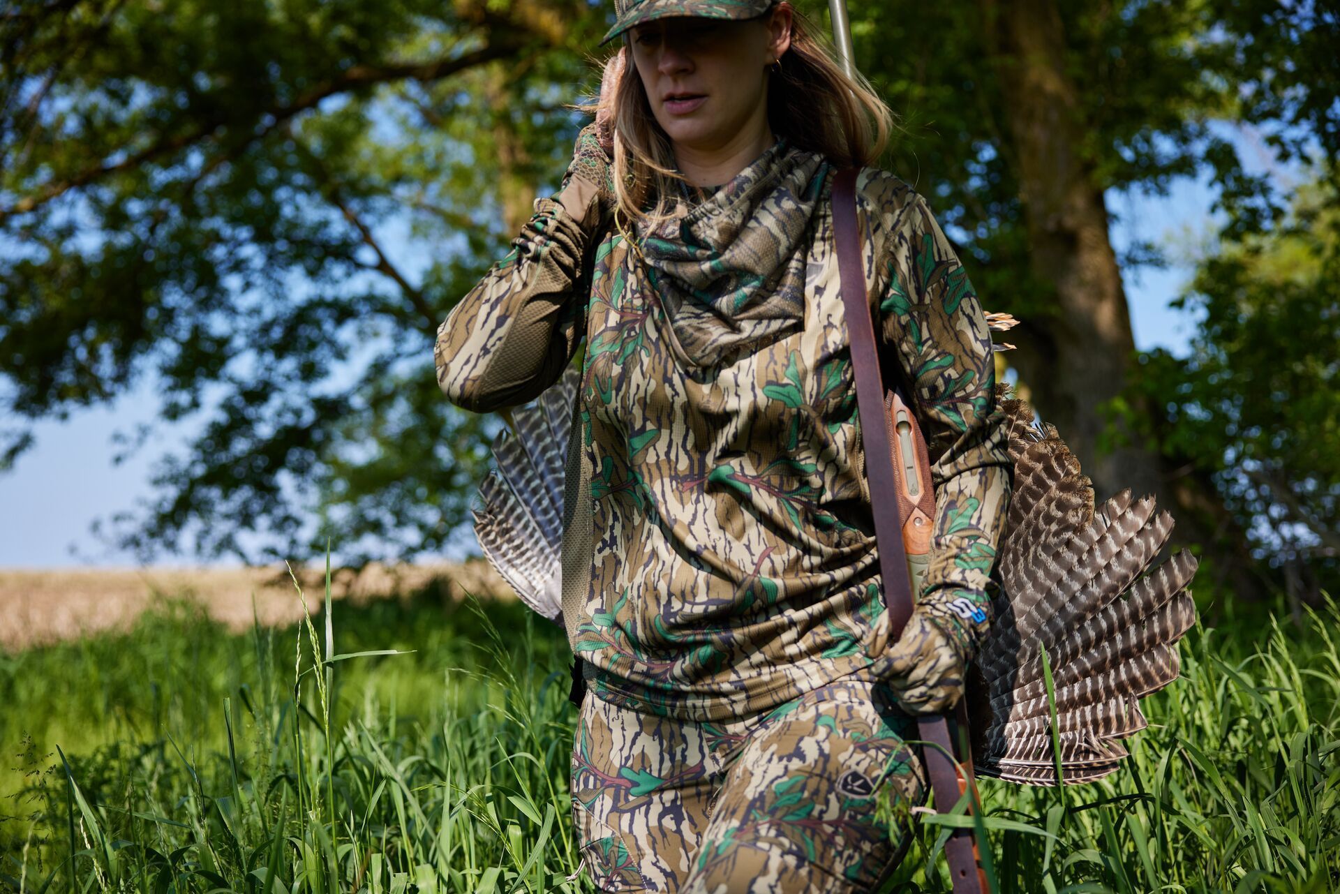 Female hunter carries turkey after hunt, spring turkey hunting for beginners concept.