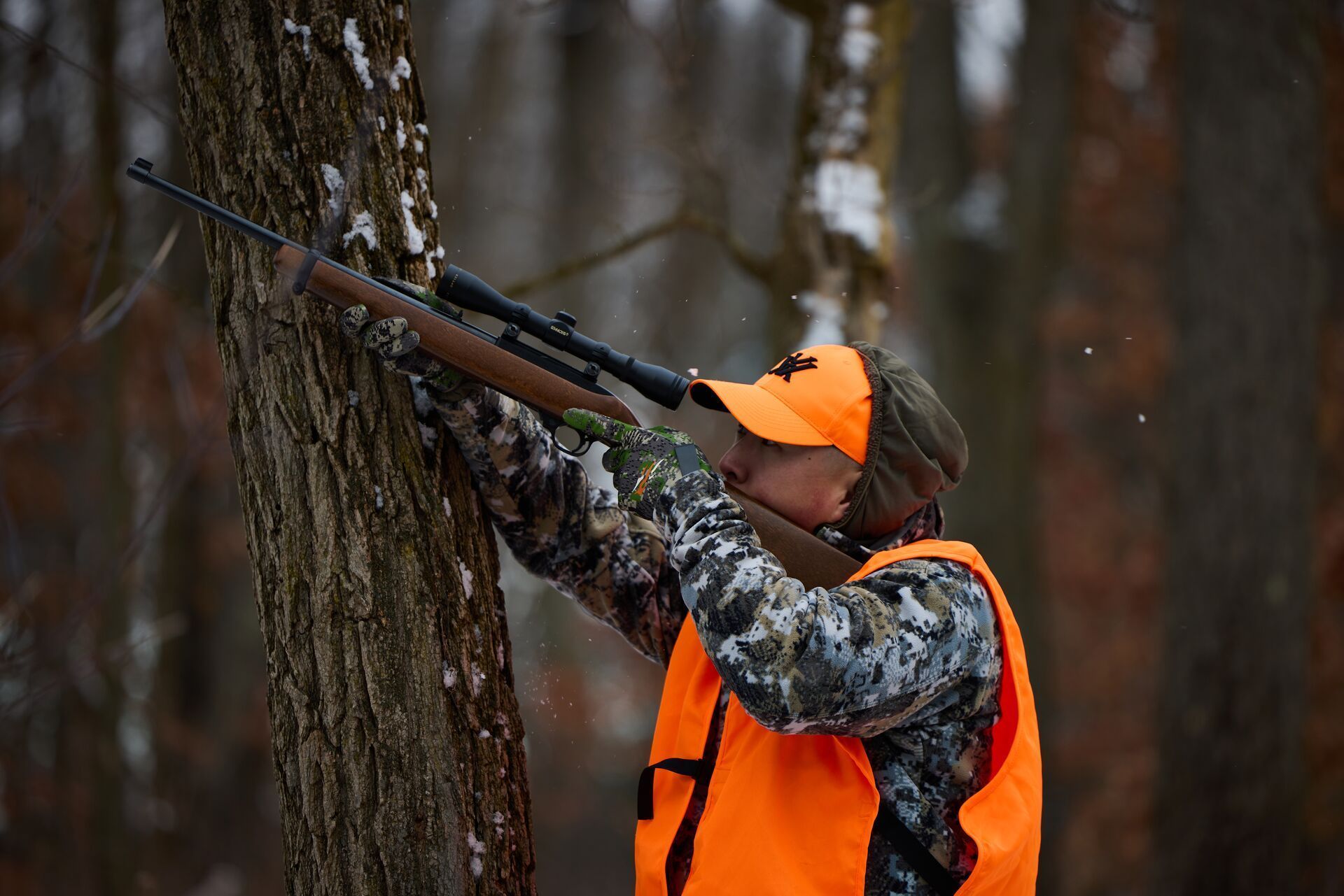 Hunter in blaze orange aims rifle, hunting for best squirrel dishes concept.