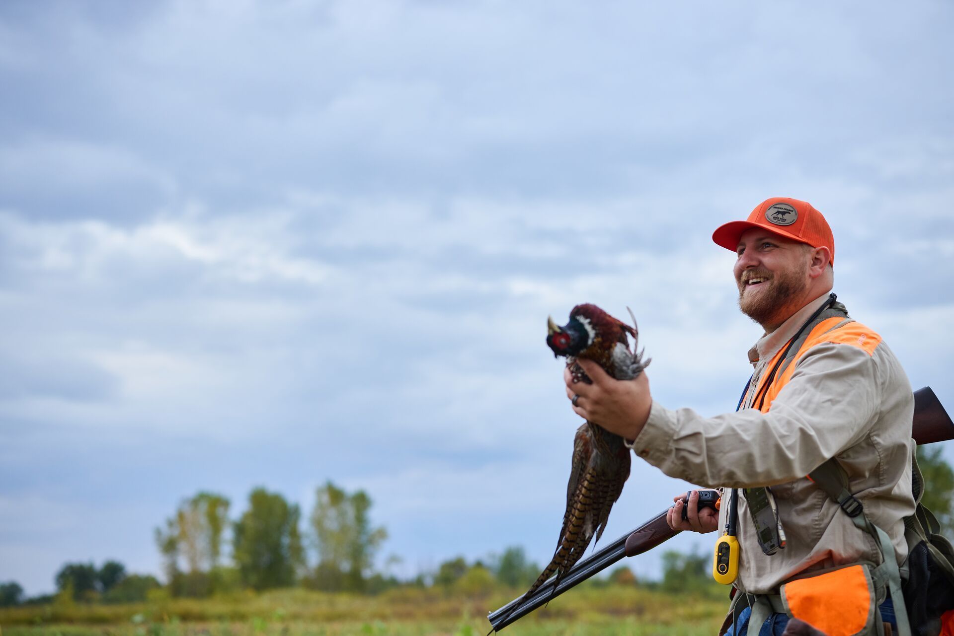Hunter smiles and holds pheasant, how to hunt pheasant concept.