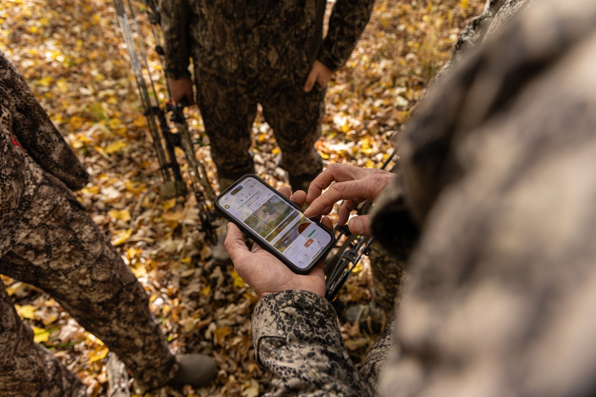 Hunters looking at a phone screen showing the HuntWise hunting app.