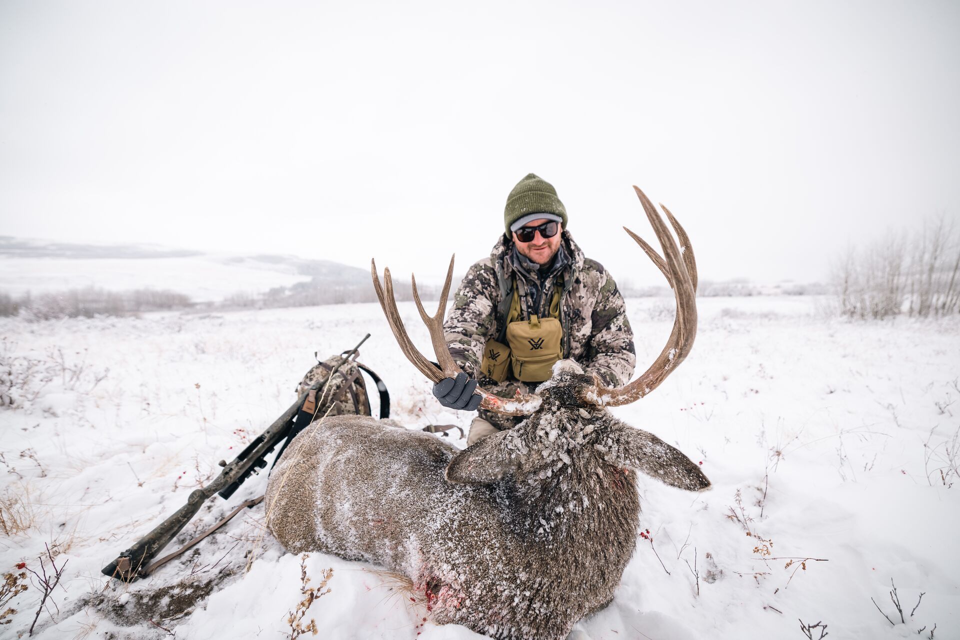 Hunter in snow with deer after hunt, deer hunting in December concept.