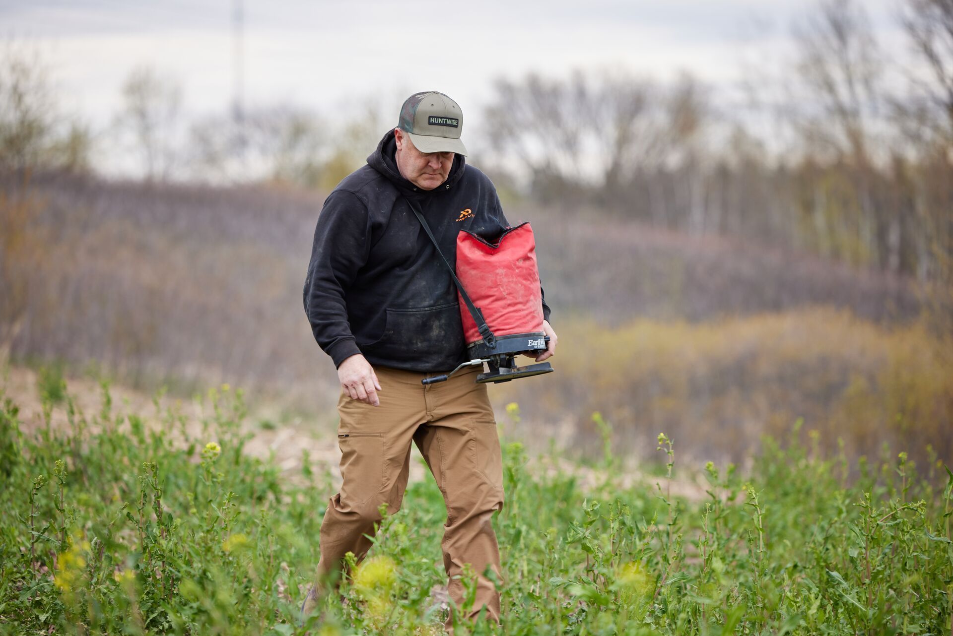 Close-up of Jeff Sturgis walking through a food plot with a seed bag, learning what do deer eat concept.