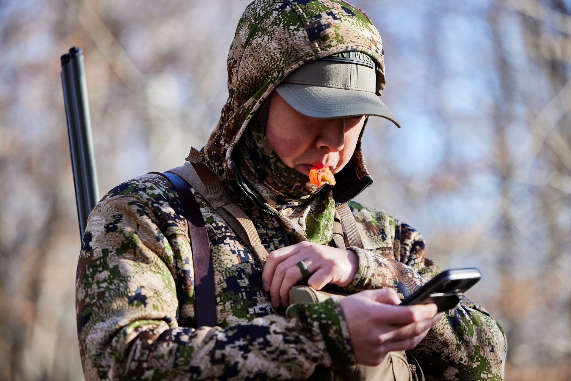 A hunter with a turkey call in his mouth during a hunt.