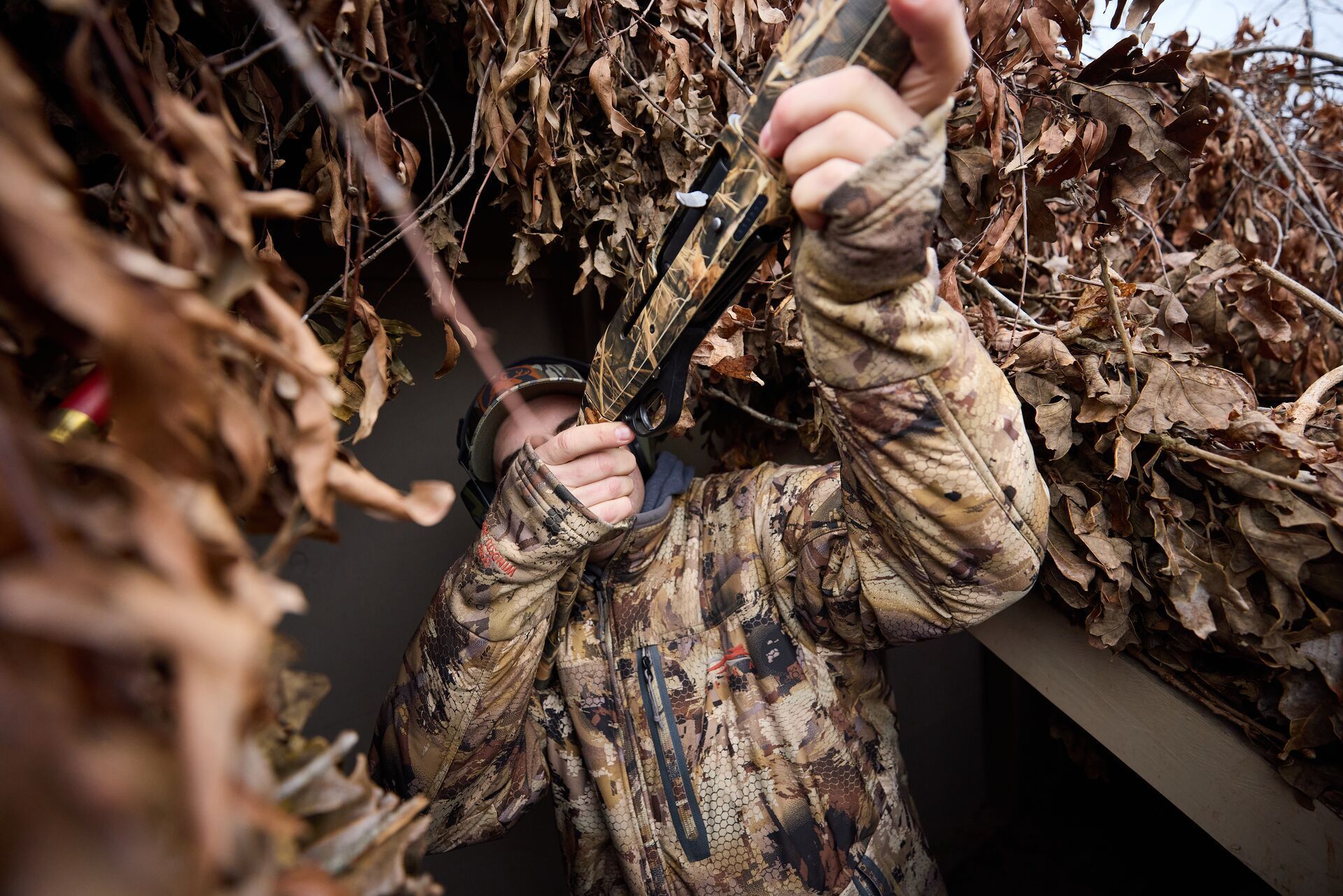 Hunter in a duck blind aims shotgun, when is duck season in Minnesota concept.