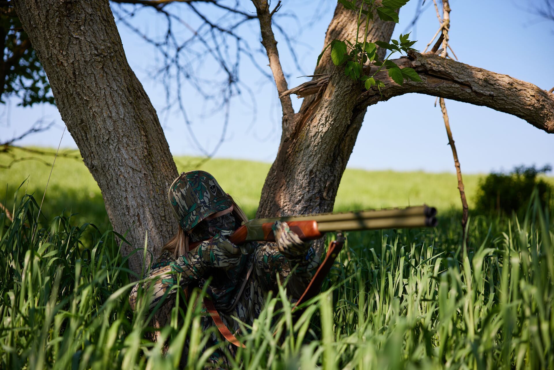 A female hunter in camo pointing a rifle, Michigan hunting concept.