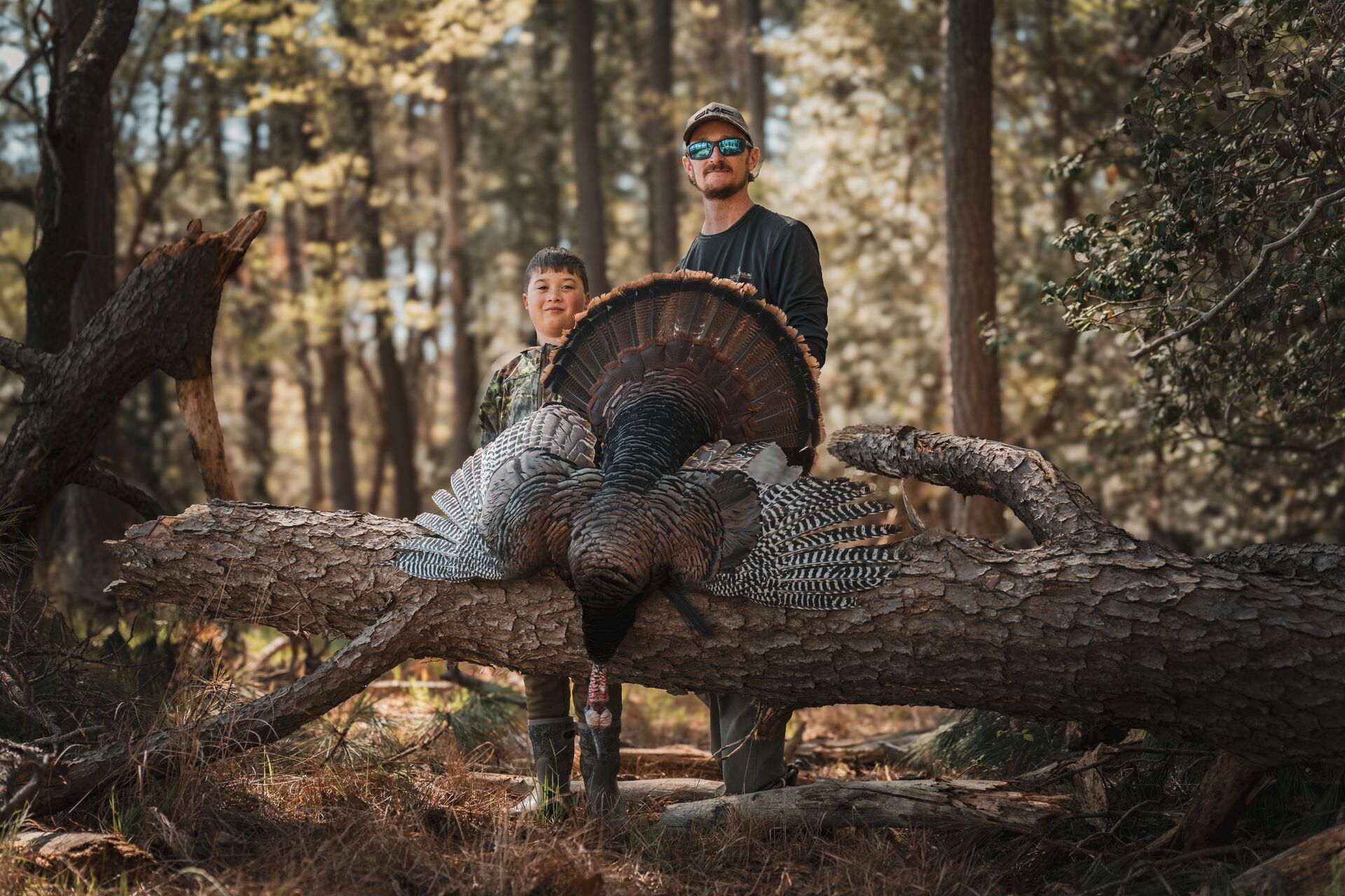 Hunter with a young hunter and a turkey harvest after a hunt, spring turkey hunting concept.