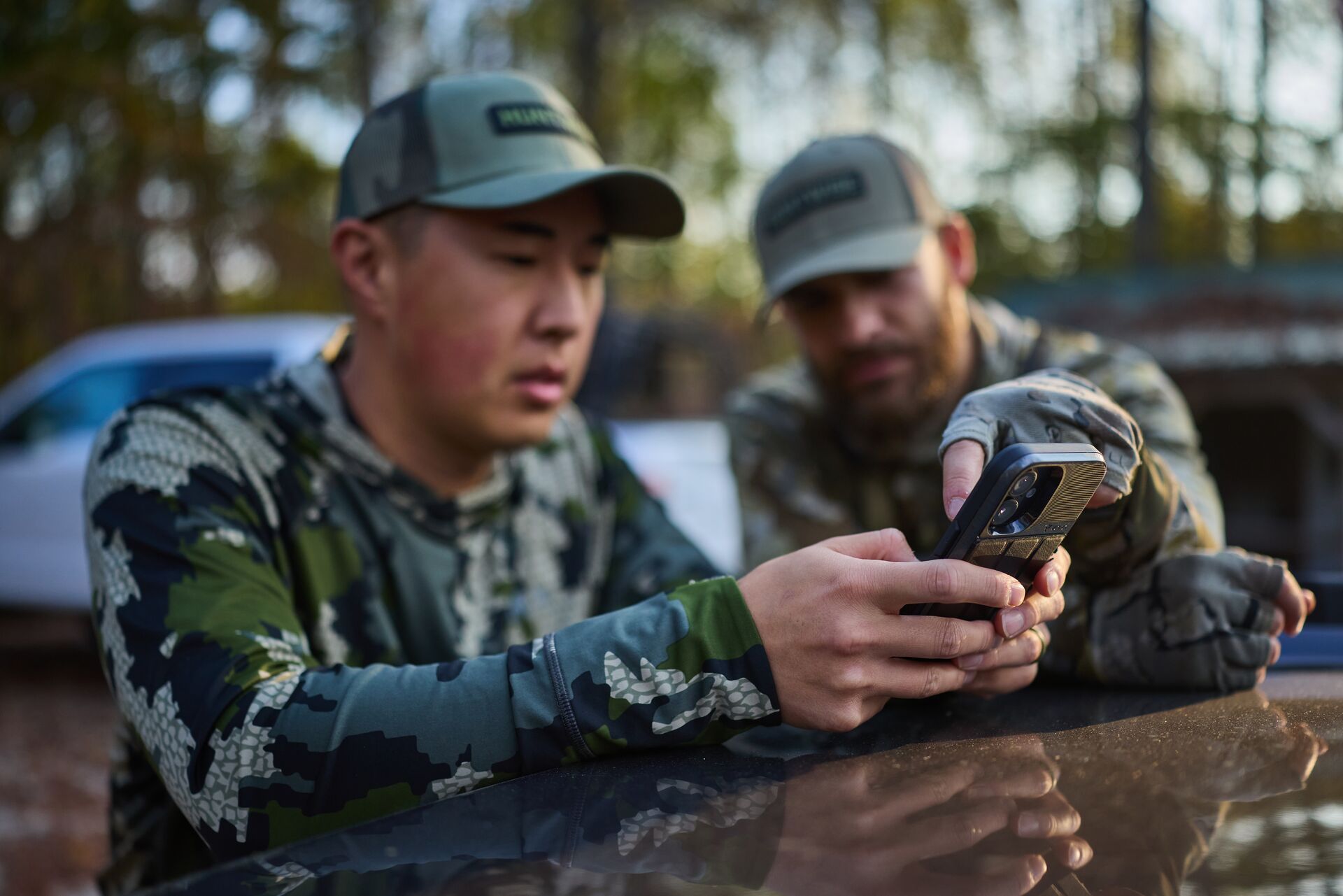 Two hunters using phone, how to use a hunting app concept.