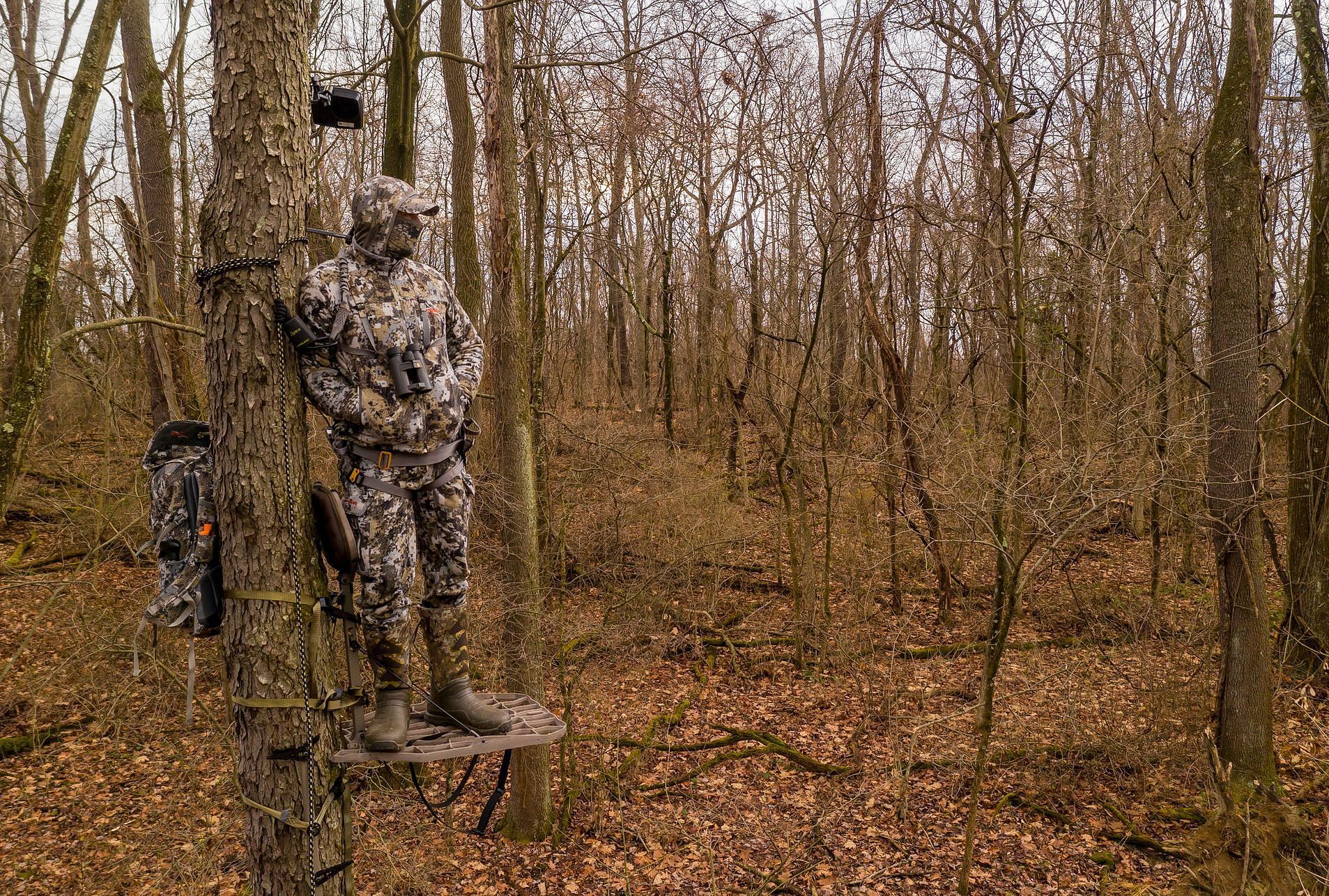 A hunter in camo stand in a tree stand, tips for muzzlerloader hunting season concept.